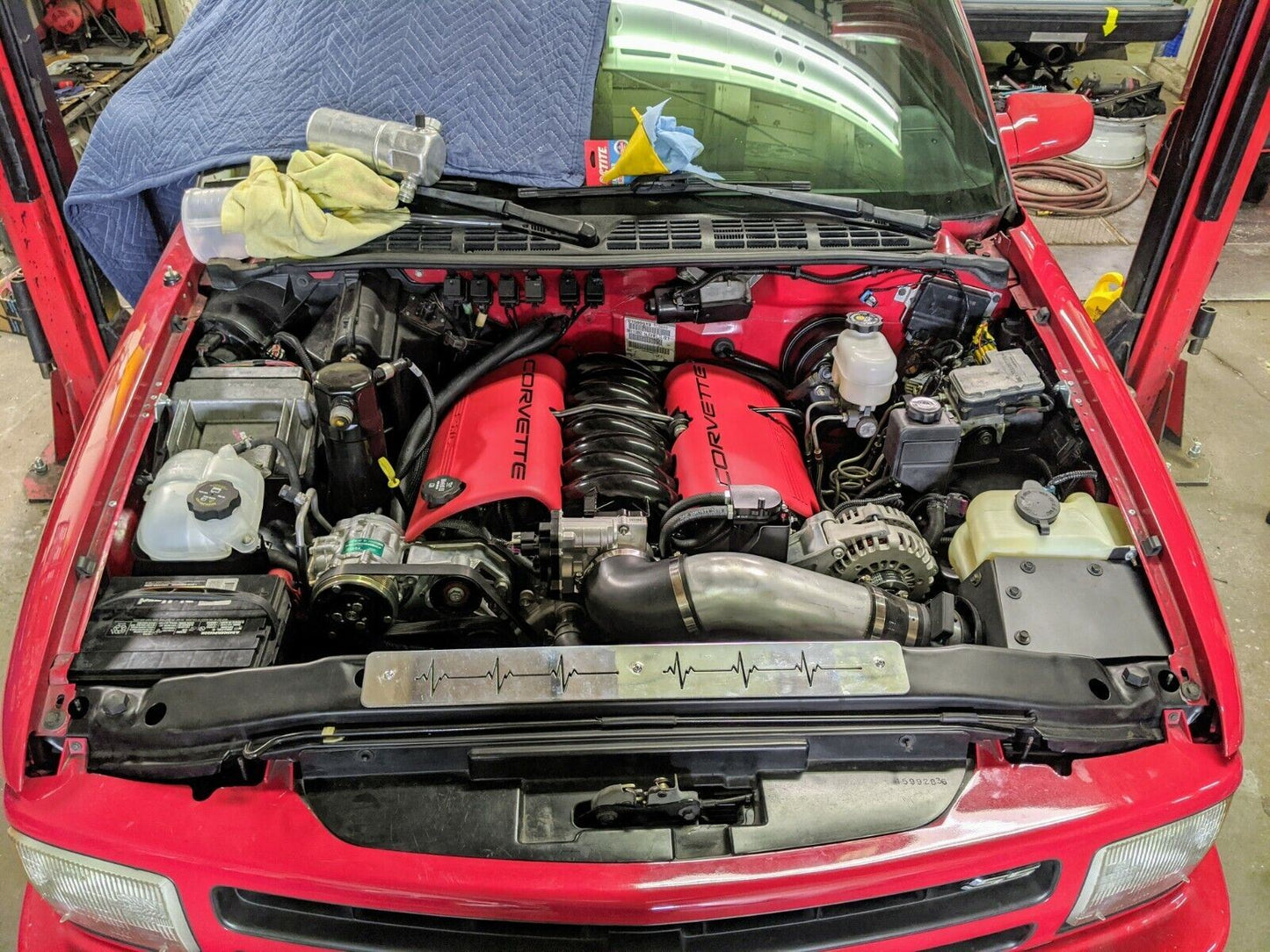 A Chevy S10 Blazer features The Ugly Trucklings 1995–2005 LS Swap Cold Air Box, custom fabricated for a factory look, installed in a clean engine bay with distinctive red valve covers and various tools and cloths nearby.