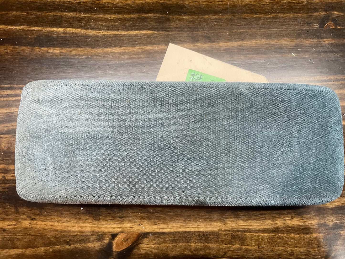A blue OEM 16.5 center armrest console lid for 1994-1997 Chevy S10 GMC Sonoma by General Motors sits on a wooden surface, with part of a brown envelope visible underneath.