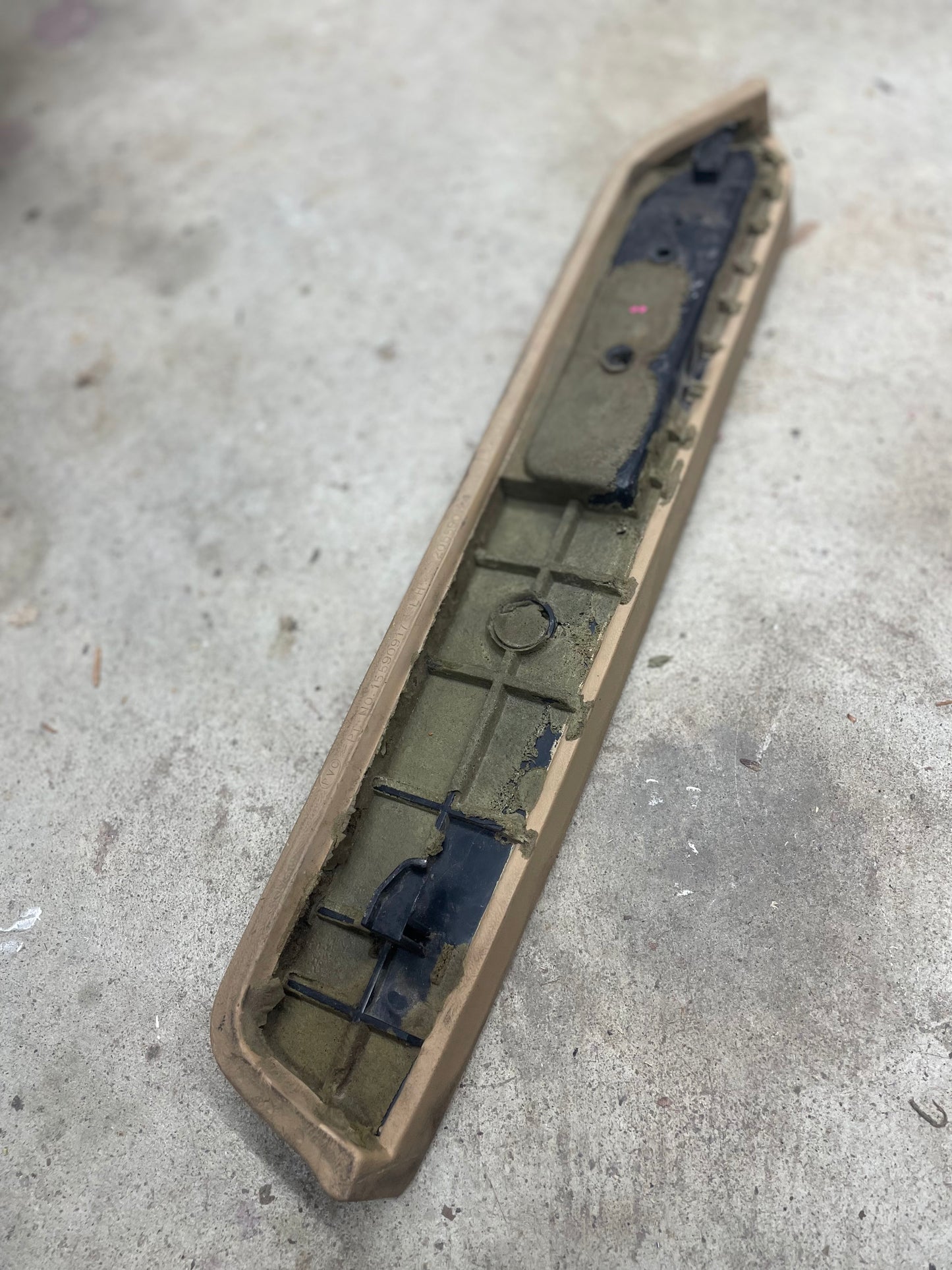 A General Motors OEM Driver Door Panel Armrest Handle in beige for 1986-1993 Chevy S10, Blazer, and more lies on a concrete surface, viewed at an angle.