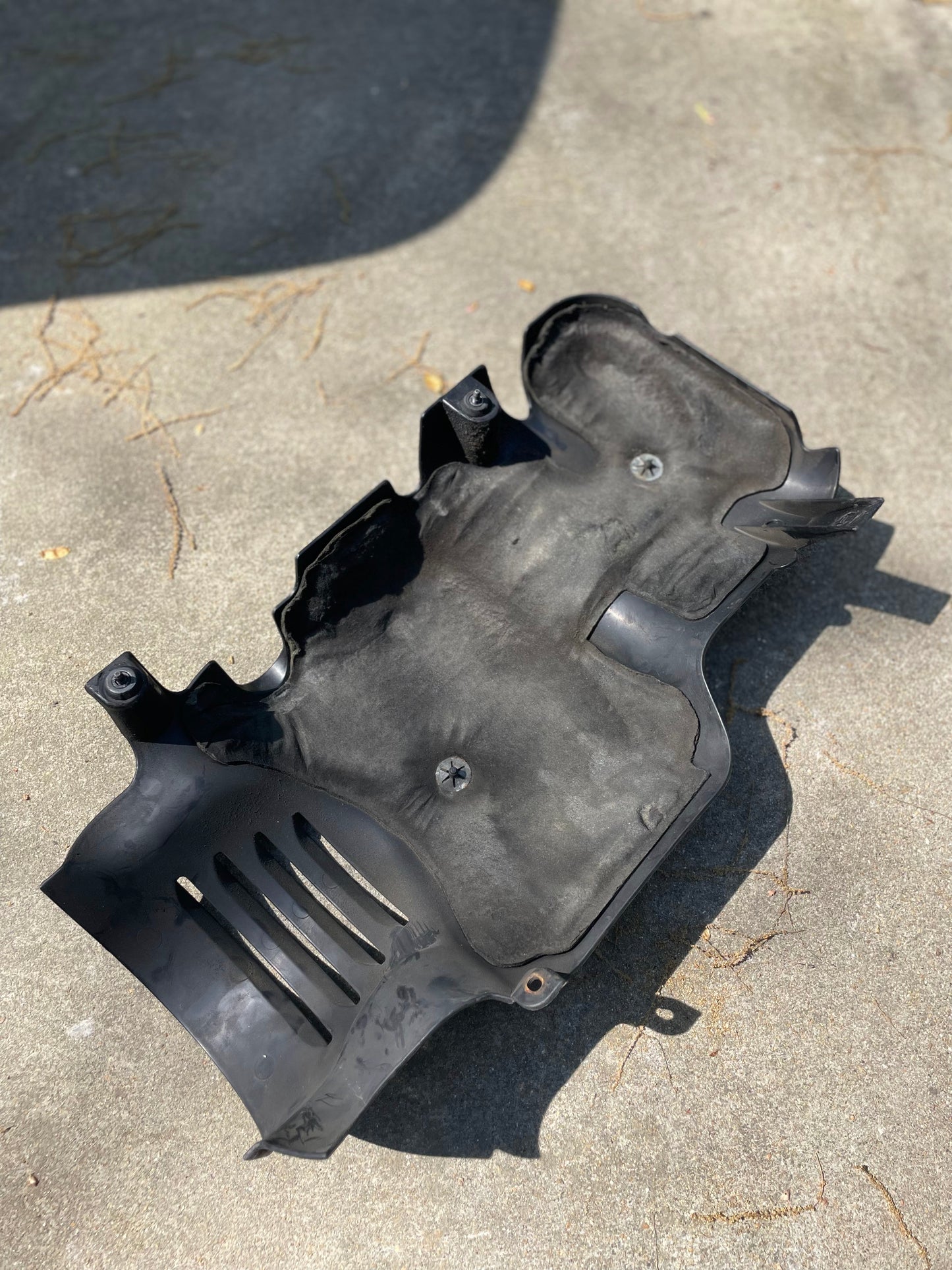 A General Motors SET Premium Vortec 6000 OEM Intake Cover for GM Trucks and LS Swaps rests on a sunlit concrete surface, with some leaves and debris nearby.