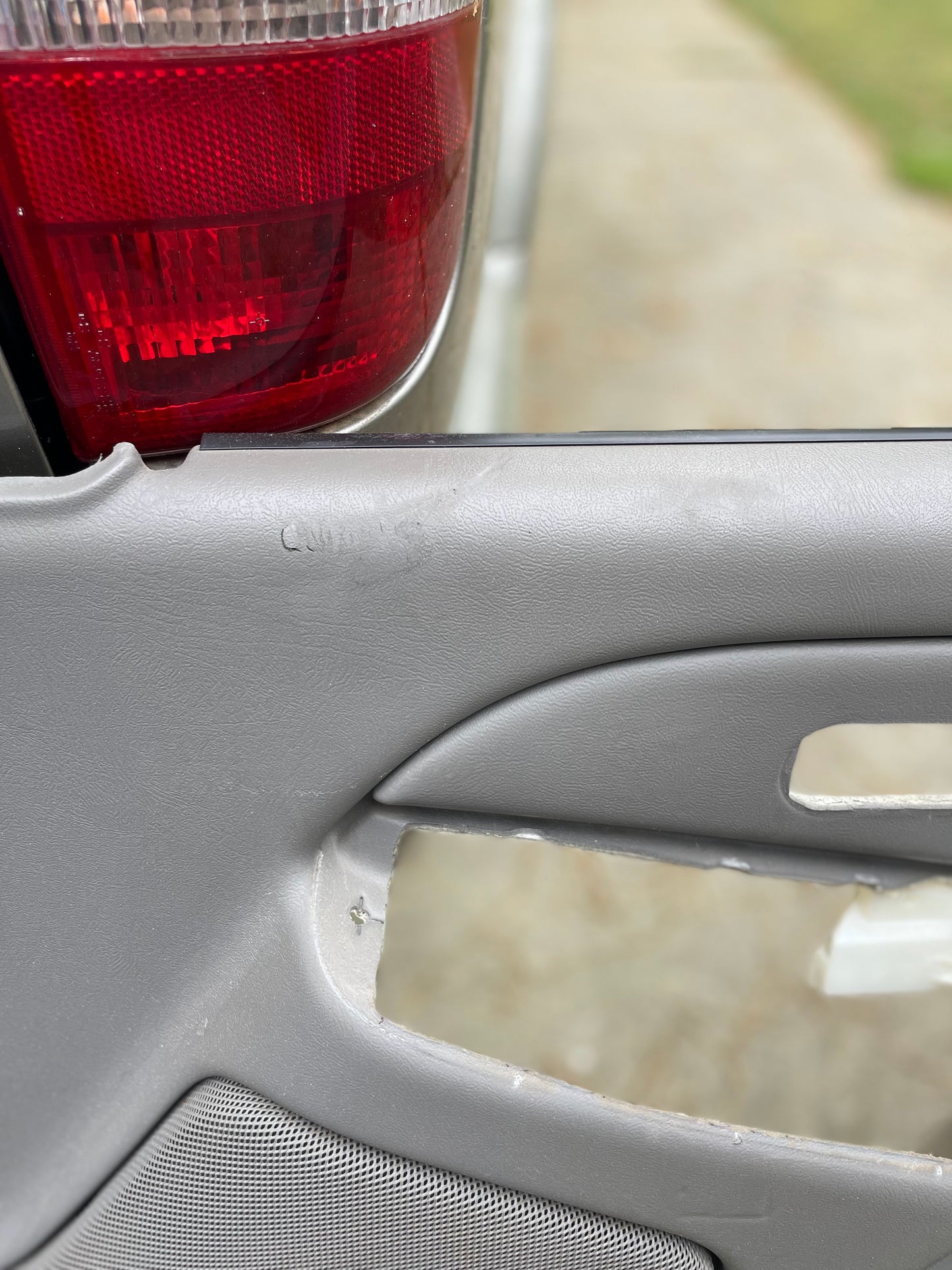 Close-up of a GM full-size trucks exterior with OEM Pair Front Leather Door Trim Panels LH RH in Light Gray by General Motors for 2003-2006 Chevy Silverado, GMC Sierra, revealing the pewter interior and red taillight.