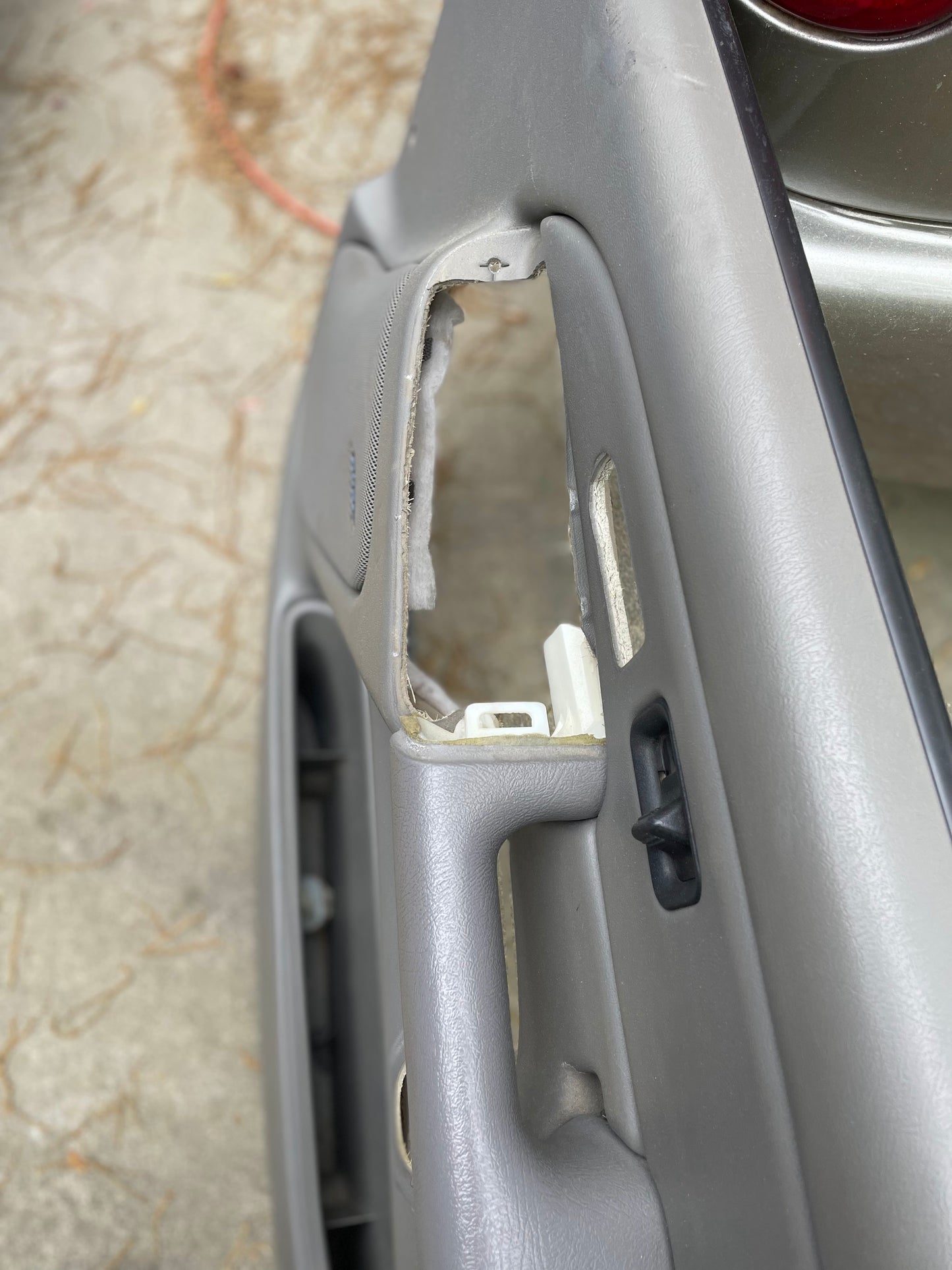 A close-up of a Pewter interior car door shows missing leather near the handle and window controls, exposing inner parts—an issue addressed by General Motors OEM Pair Front Leather Door Trim Panels LH RH in Light Gray for 2003-2006 Silverado/Sierra.