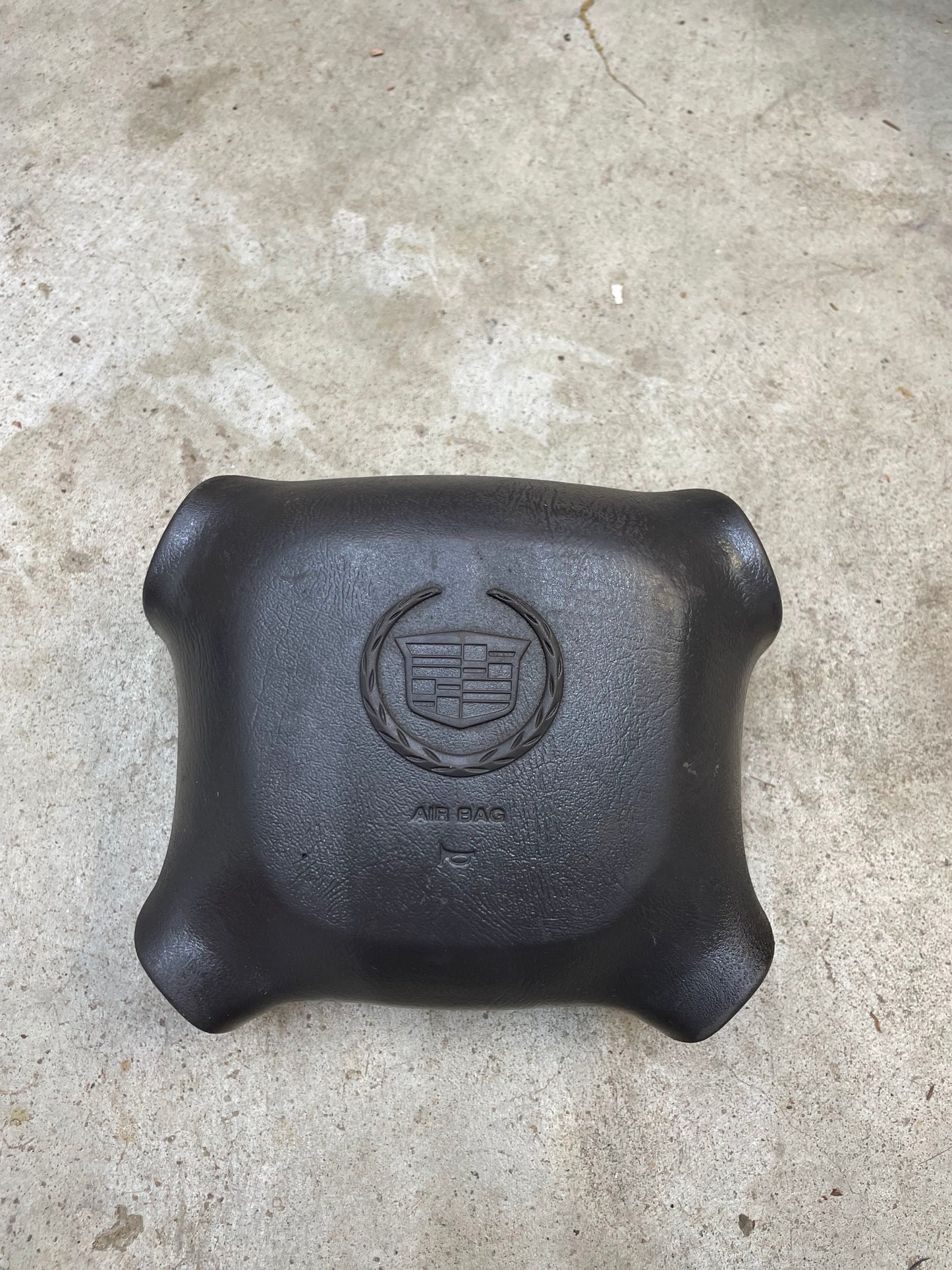 A General Motors KIT Leather w/Wood Steering Wheel with Radio Controls from Escalade (1995-2005 GM Trucks), shown on a concrete surface.