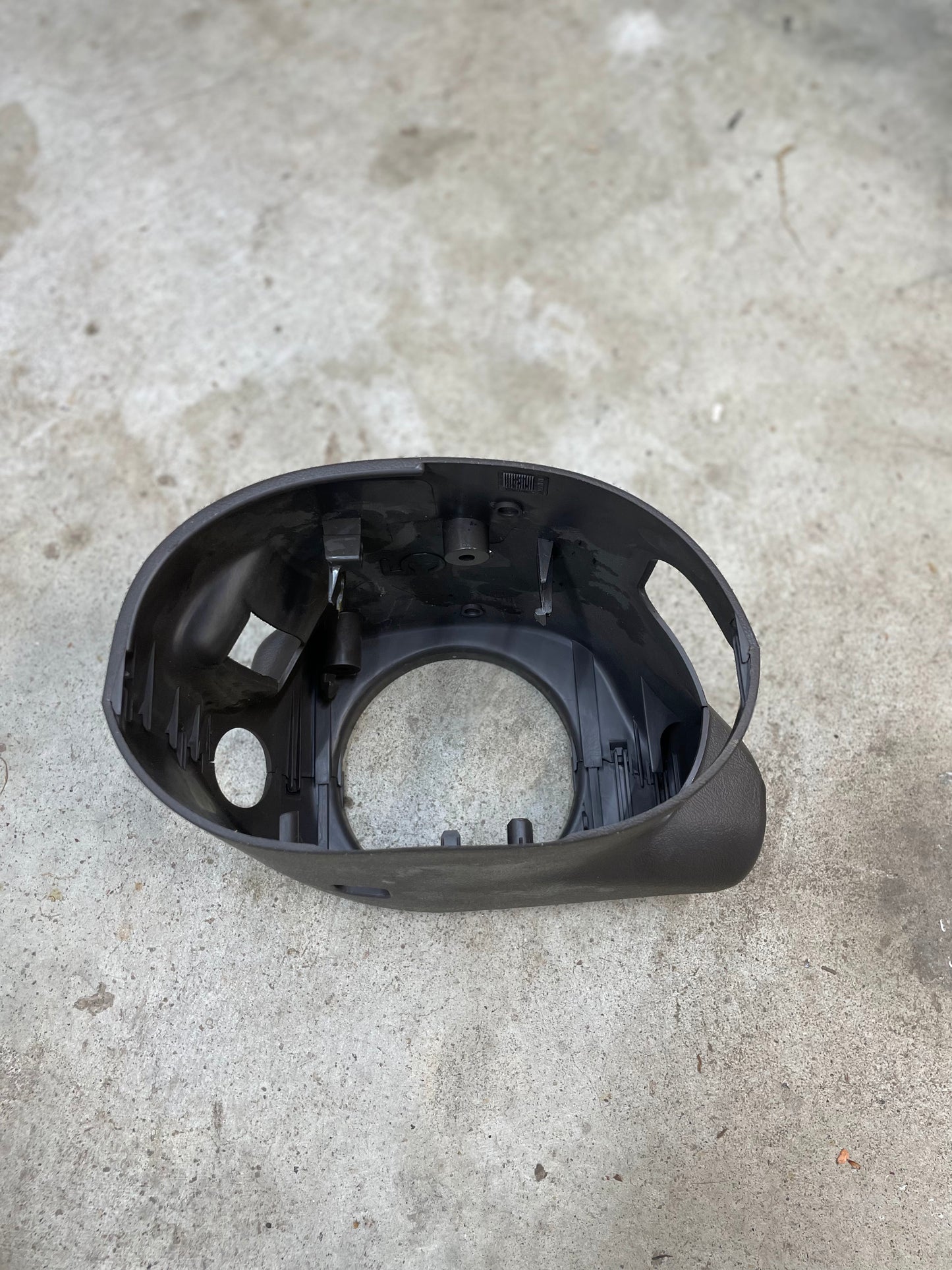 A KIT Leather w/Wood Steering Wheel & Radio Controls from Escalade (1995–2005 GM Trucks) by General Motors, showing some scratches and wear, is displayed on a light gray concrete floor.