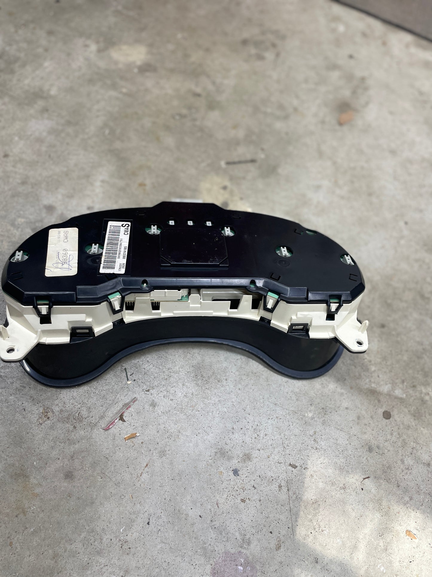 A General Motors OEM Tested Instrument Cluster with Tachometer for 2001-2005 Chevy S10 or Blazer (with Console Shifter) is shown face down, displaying its black and white back housing, barcode sticker, and multiple connector ports.