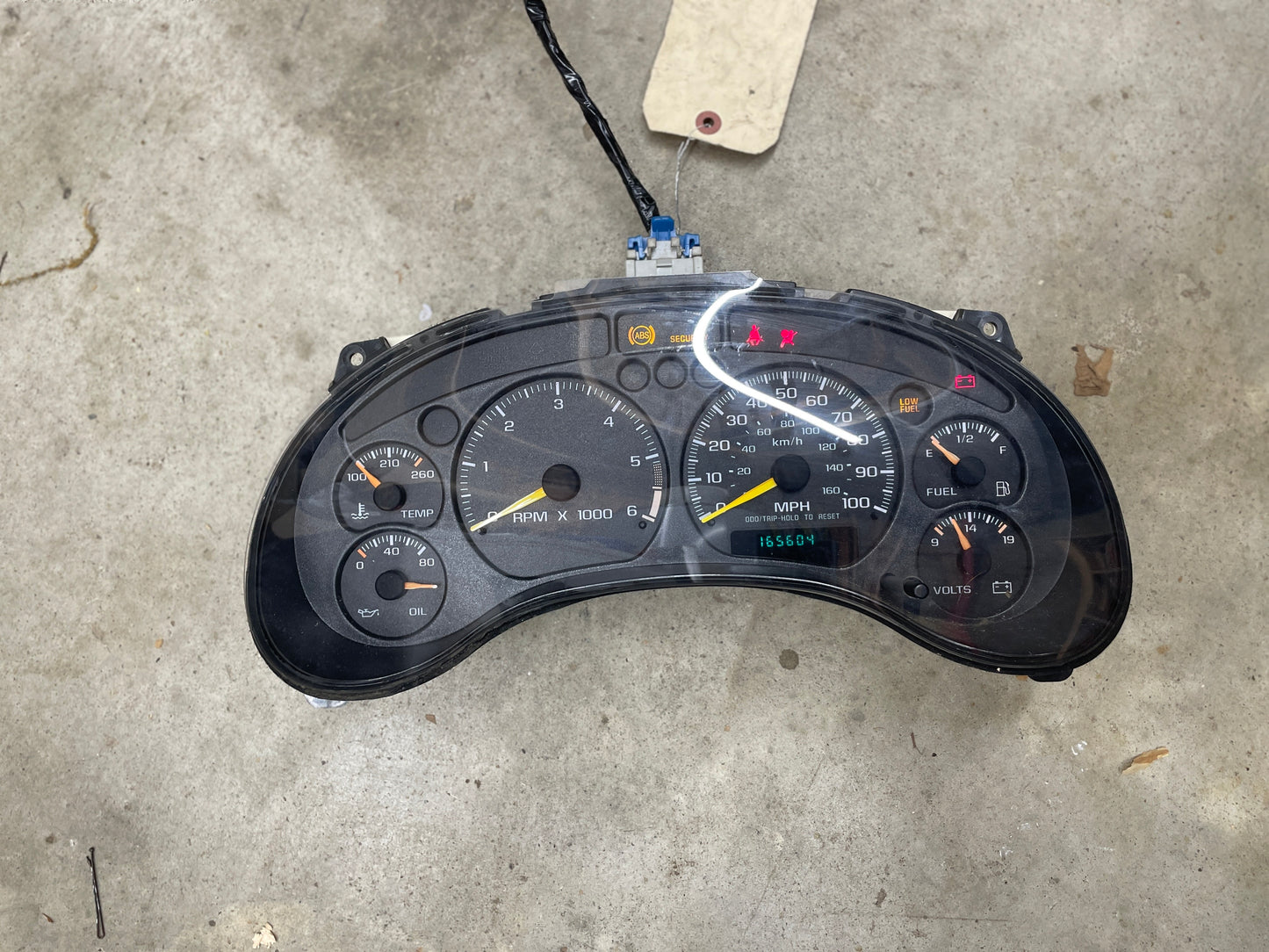 A General Motors OEM Tested Instrument Cluster with tachometer for 2001-2005 Chevy S10 or Blazer with console shifter (4.3 V6 manual). Digital odometer shows 165,604 miles; displays RPM, speed, oil pressure, fuel, voltage, and engine temp.