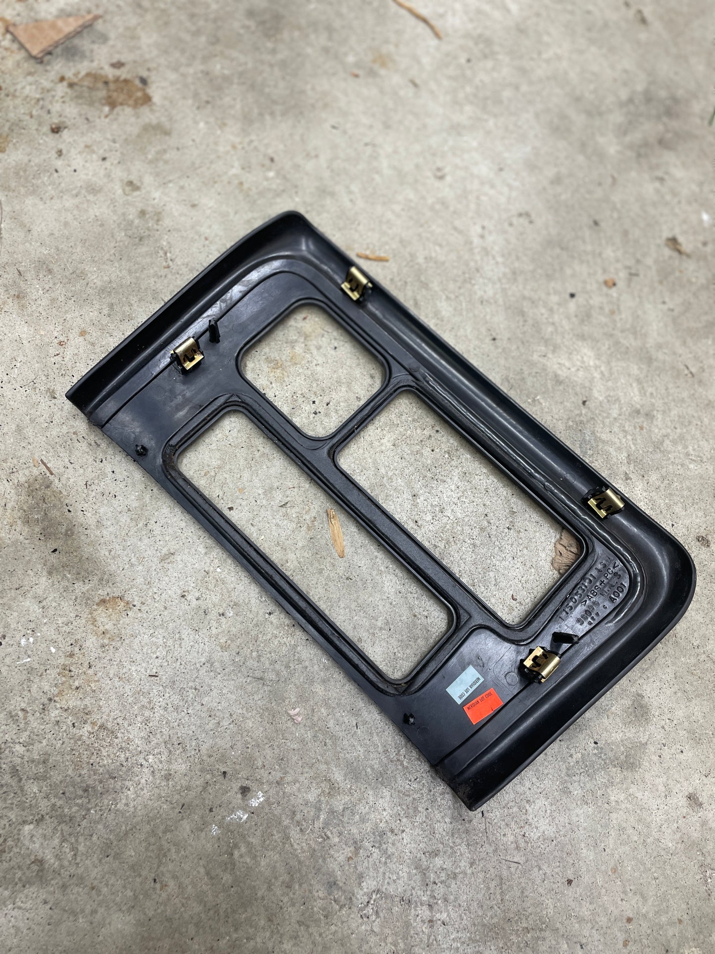 A General Motors OEM Center Console Front Bin with Dark Woodgrain Trim for 2001-2002 GMC Sierra C3 and Yukon Denali is shown on a concrete surface, featuring labels identifying the product name and fitment.