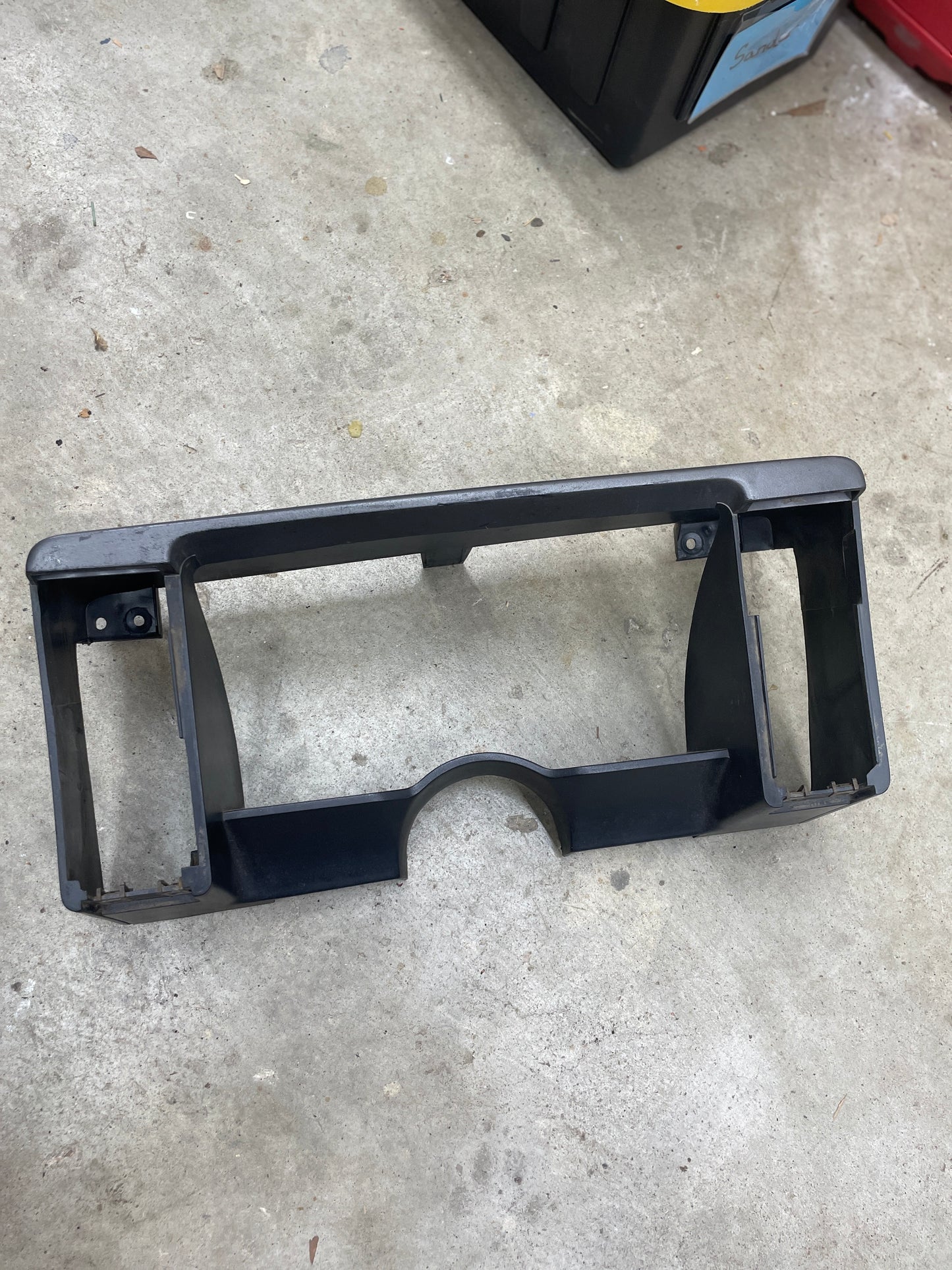 A General Motors OEM gray instrument cluster dash bezel for 1986–1993 Chevy S10 Blazer, GMC S15, and more rests on a gray concrete floor.