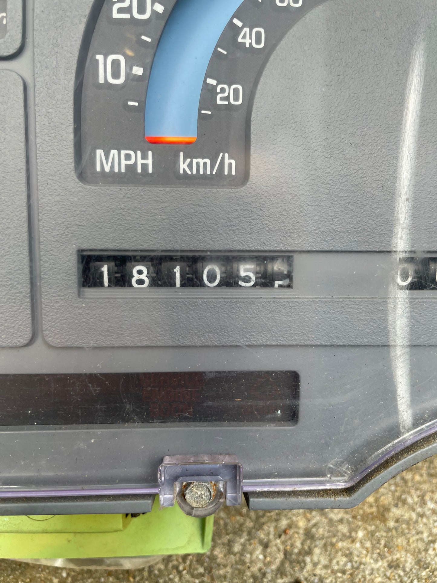 Close-up of a General Motors OEM Instrument Cluster with Mechanical Speedo & PRNDL for 1986-1989 Chevy S10 Blazer, showing both MPH/km/h. Odometer reads 18,105 miles; lower panel displays a screw and dashboard edge.