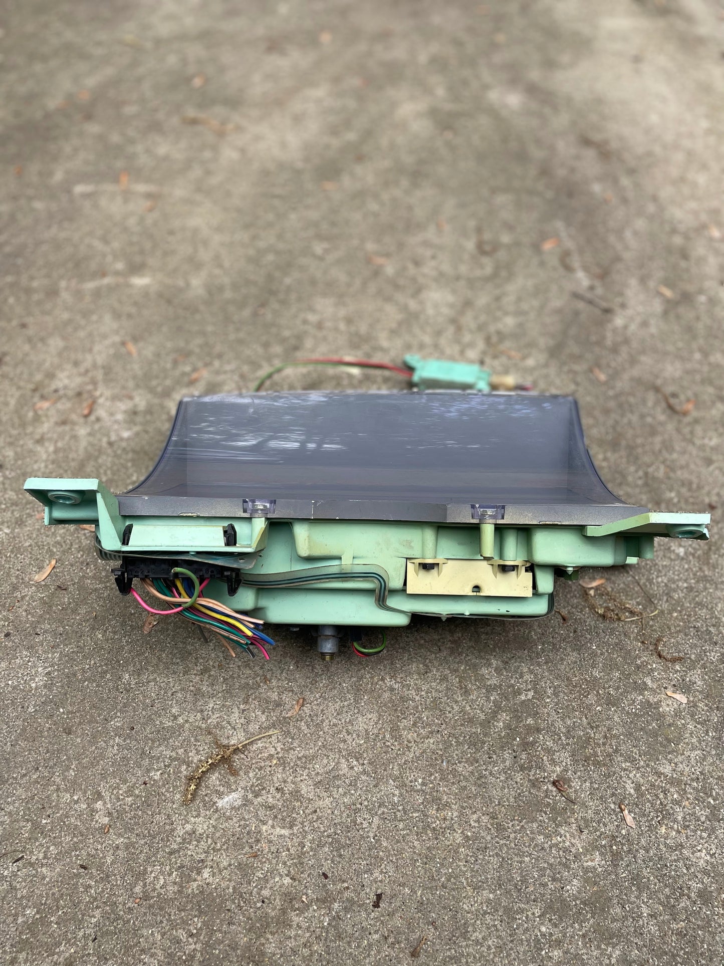 A vintage CRT monitor with exposed wires sits on concrete outdoors, resembling a General Motors OEM Instrument Cluster with Mechanical Speedo and Manual Transmission for 1986-1990 Chevy S10 Blazer.