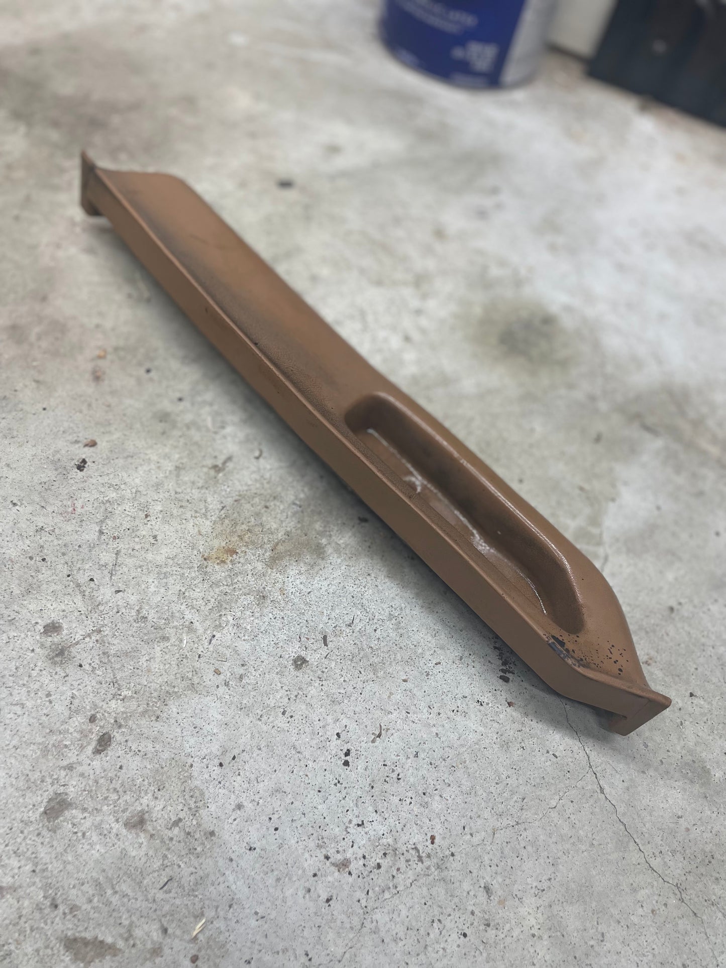 A beige OEM General Motors passenger door panel armrest handle for 1986–1993 Chevy S10, Blazer, and more rests on concrete; the item shows slight rust.