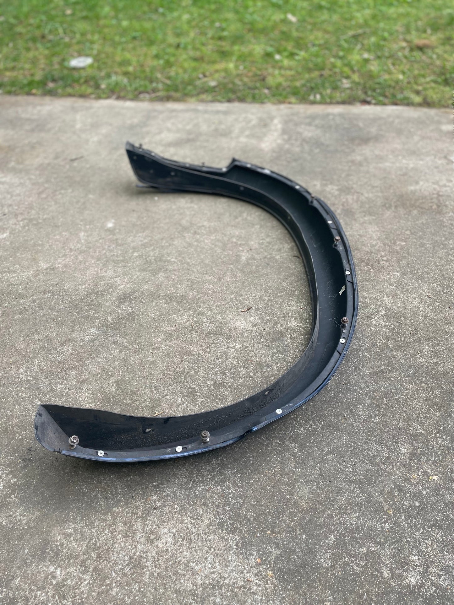 A blue pair of OEM rear ZR2 bed flare extensions for 1994-2004 Chevy S10 or GMC Sonoma by General Motors lies on a concrete surface, with some visible wear; green grass is seen in the background.