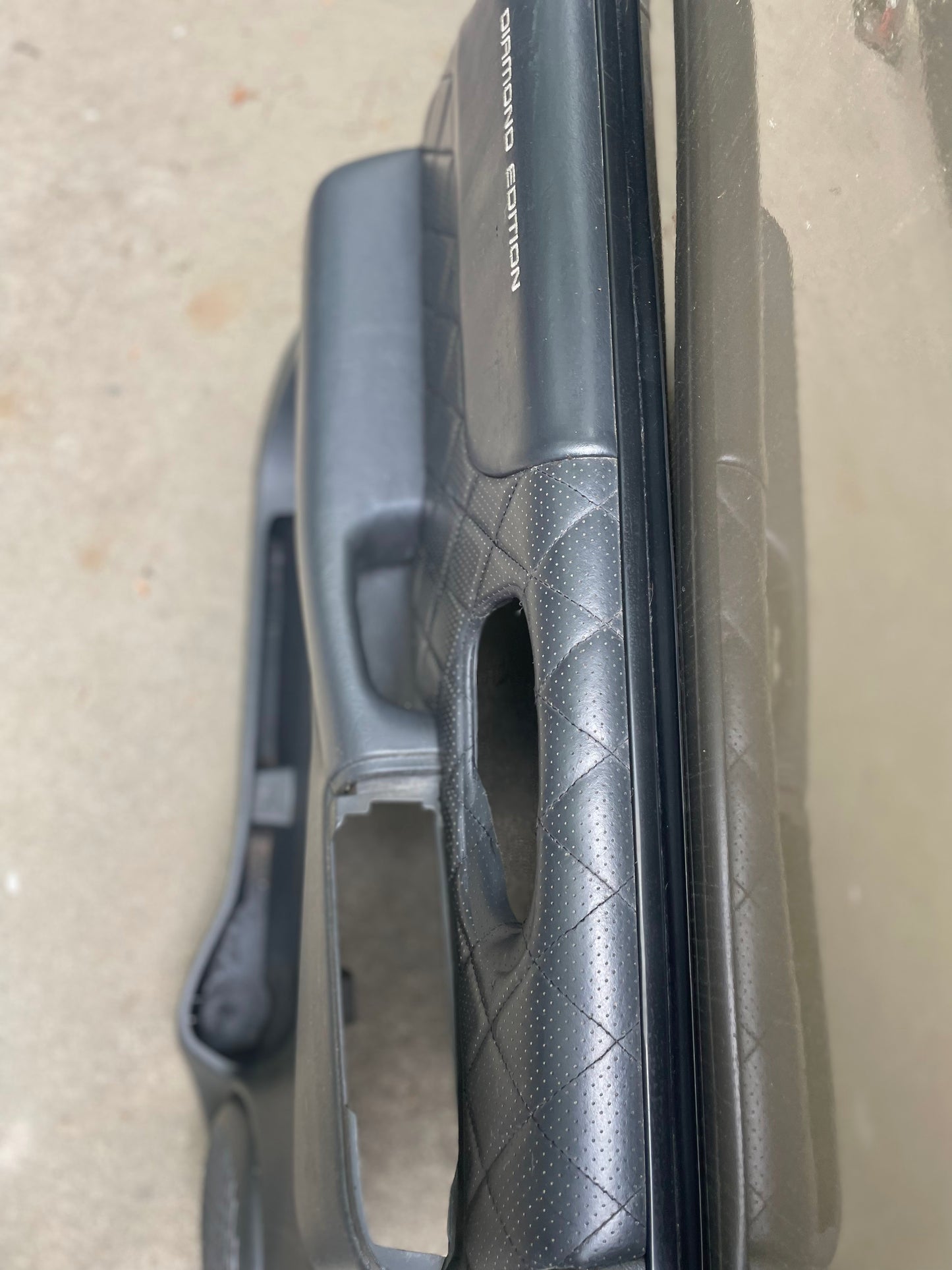 Close-up of a dark gray OEM General Motors leather diamond door panel for 1998-2005 Chevy S10 or GMC Sonoma, featuring two rectangular openings and DIAMOND EDITION in white—fits factory interiors.