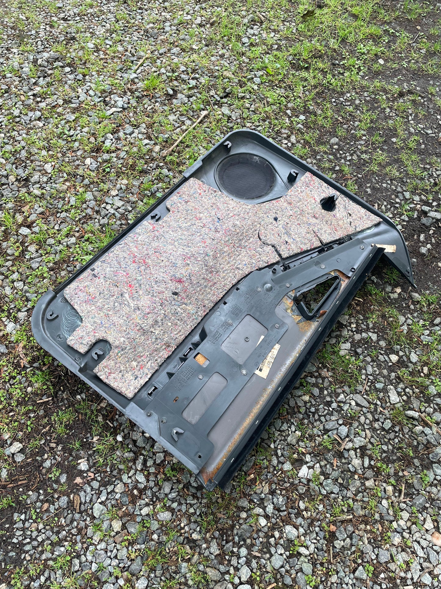 A pair of OEM General Motors front power door panels in dark gray with woodgrain, made for 1994-1997 Chevy S10 and GMC Sonoma, is shown outdoors with exposed insulation on a gravel and grass surface.