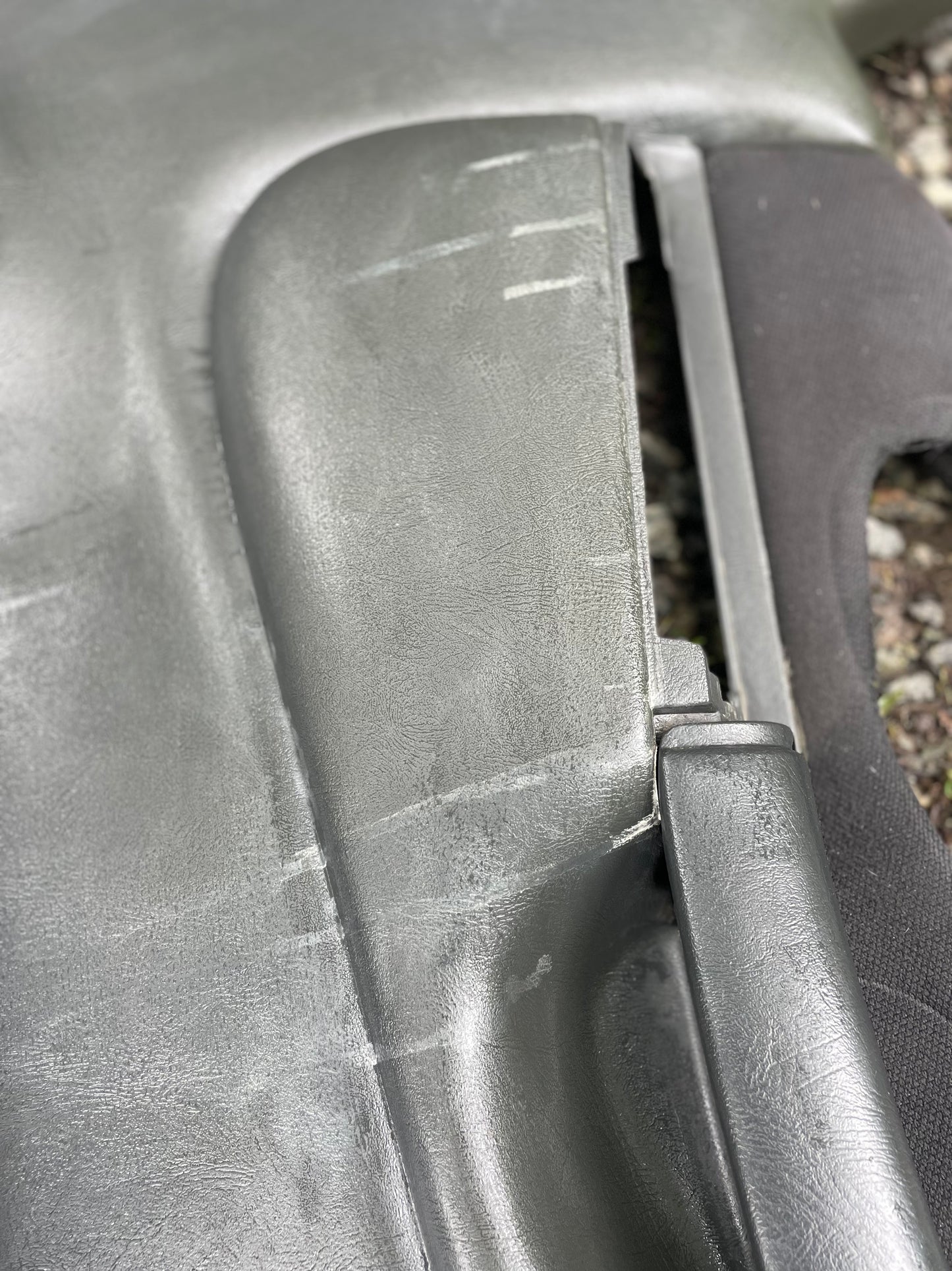 Close-up of a scratched gray metallic surface and hinge, with black textured material—typical of the General Motors OEM Pair of Front Power Door Panels in Dark Gray for 1998-2005 Chevy S10, GMC Sonoma, and similar models.