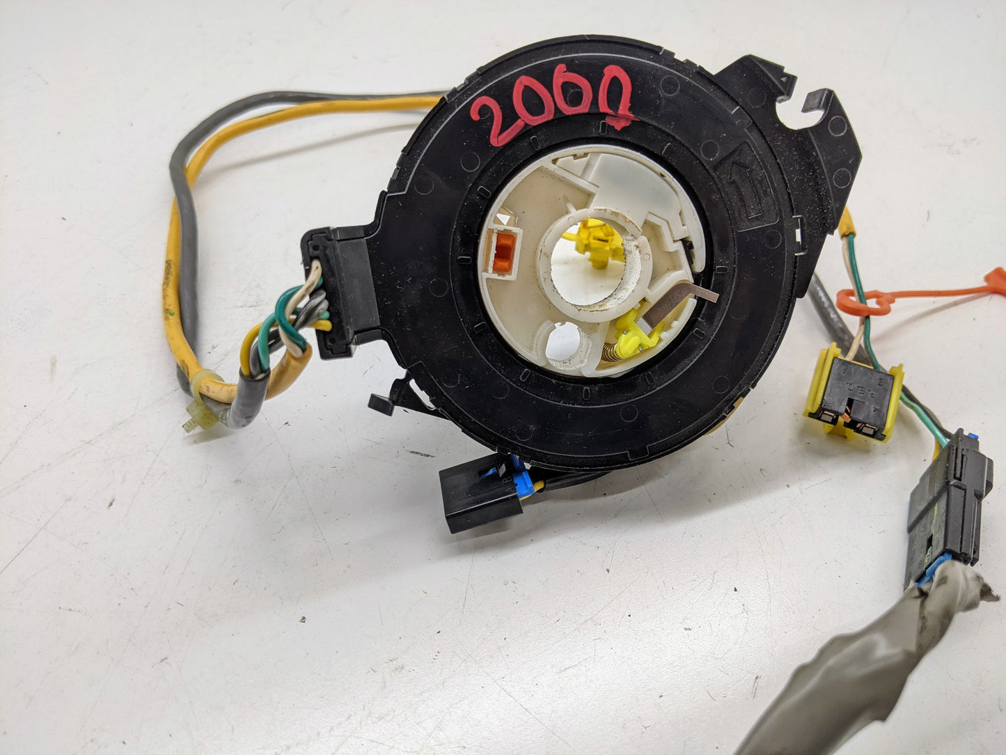 A General Motors OEM Steering Wheel SRS Air Bag Clock Spring with radio controls, tested for 2000-2003 Chevy S10 Blazer (and more), appears black and circular with wires, connectors, and 2060 in pink on top, on a white surface.