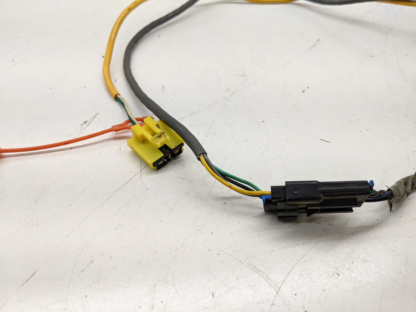 Close-up of General Motors OEM Steering Wheel SRS Air Bag Clock Spring with radio controls, showing orange, yellow, black, green, and blue wires for 2000-2003 Chevy S10 Blazer on a white surface; unit is tested.