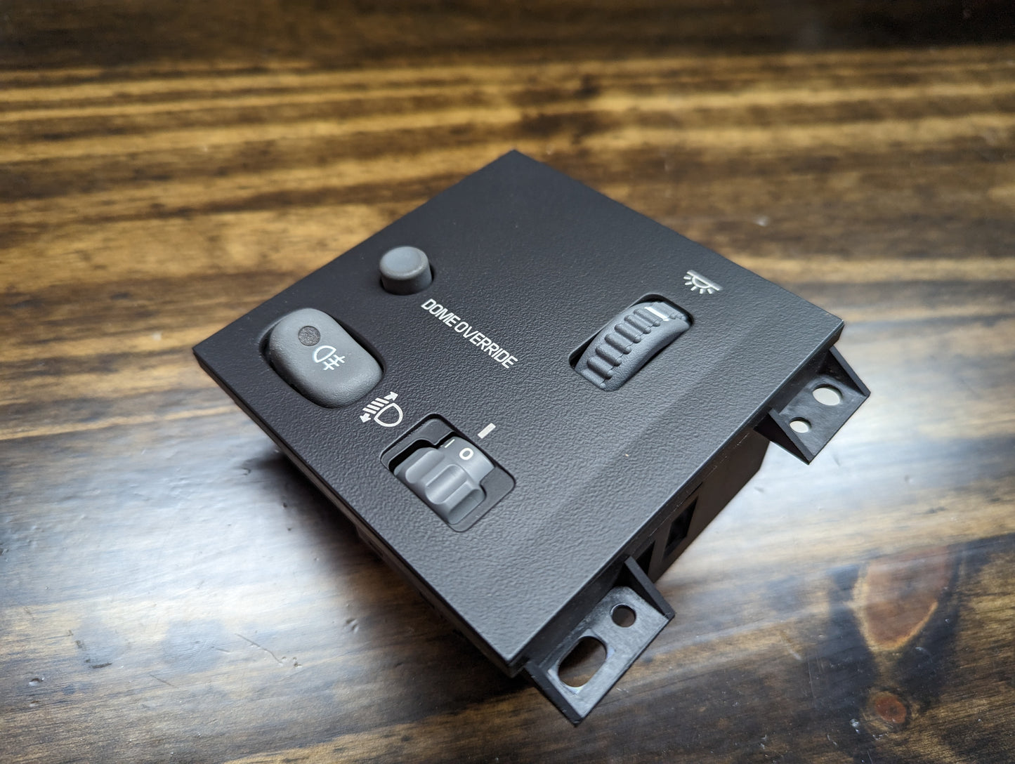 A General Motors NOS headlight switch with rear fog and level adjust for 1998-2005 Chevy S10, Blazer, GMC Sonoma, and Jimmy is shown on a wooden surface.