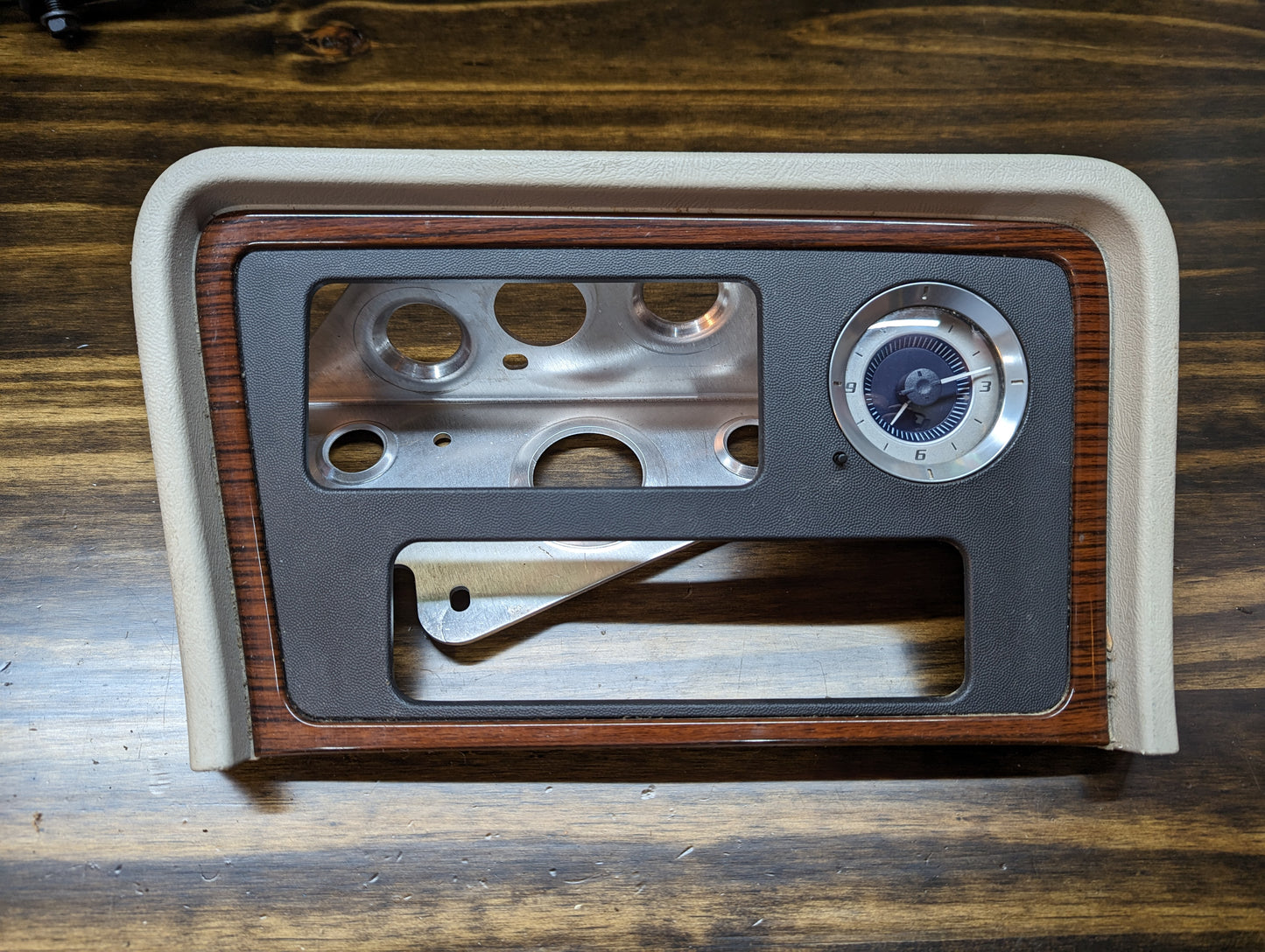 The General Motors OEM Center Console Front Bin Woodgrain Trim with Clock for 2002 Cadillac Escalade features wood and beige accents plus gauge cutouts, making it perfect for restoring your SUV’s original look.