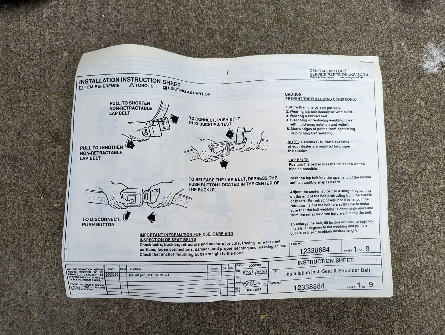 An installation instruction sheet for the General Motors NOS Driver Seat Belt Retractor & Buckle in Gray for 1982–1993 Chevy S10 and GMC S15 is laying on a rough concrete surface, showing diagrams and steps for use.