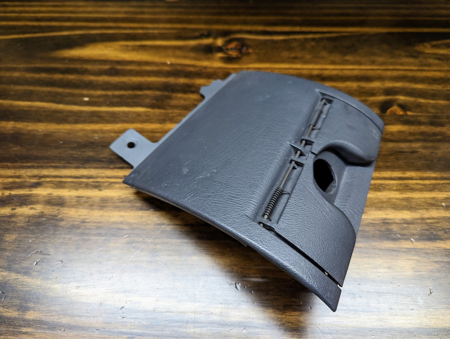 A dark gray OEM 3 Port 12V Aux Panel Ash Tray Delete from a 1998-2000 GMC Envoy by General Motors, shown on a wooden surface.
