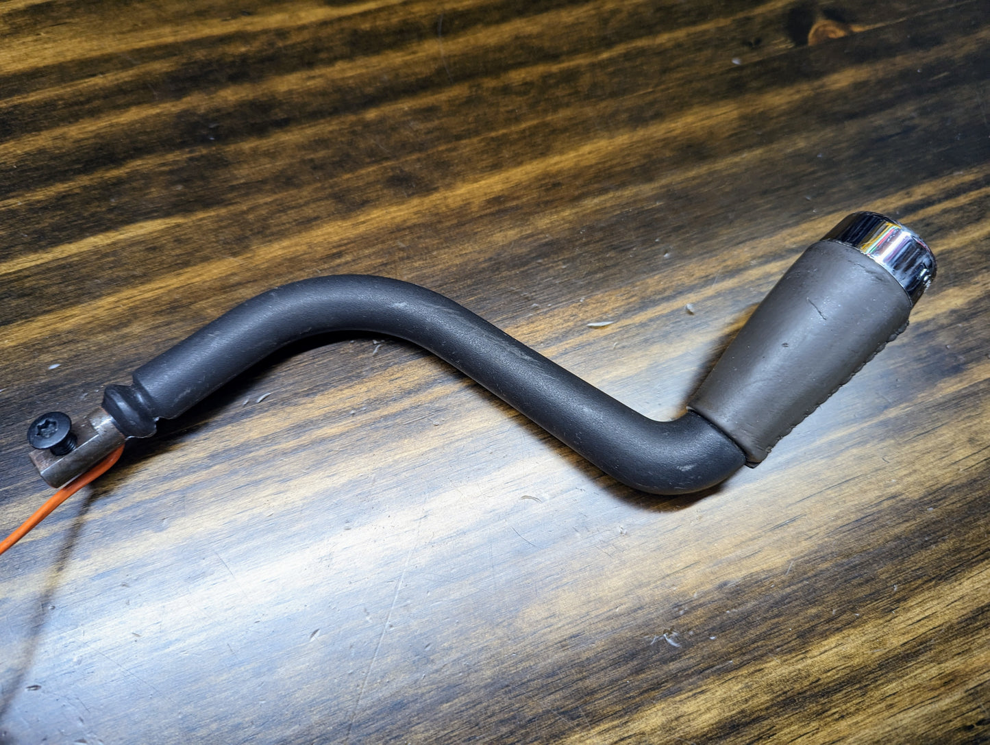 A General Motors OEM Column Shift Lever with gray leather wrap, designed for 1999-2006 GM full-size trucks, rests on a wooden surface.