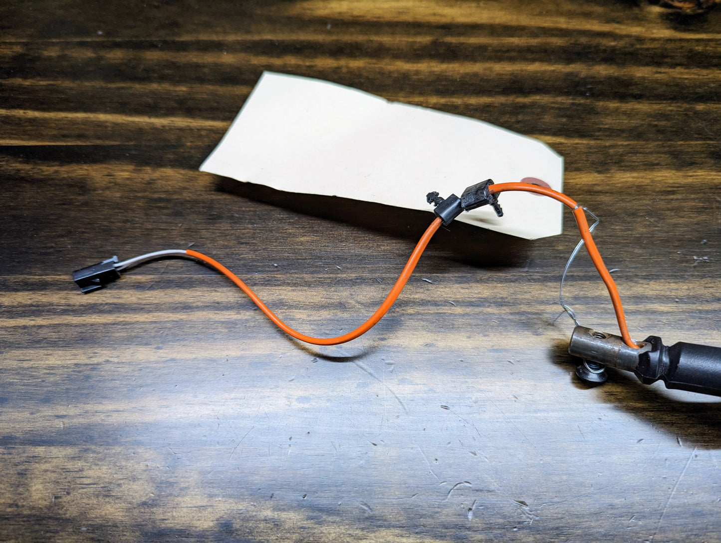 An OEM Column Shift Lever with gray leather wrap, made by General Motors for 1999-2006 GM full-size trucks, sits on a wooden surface with a piece of white paper in the background.