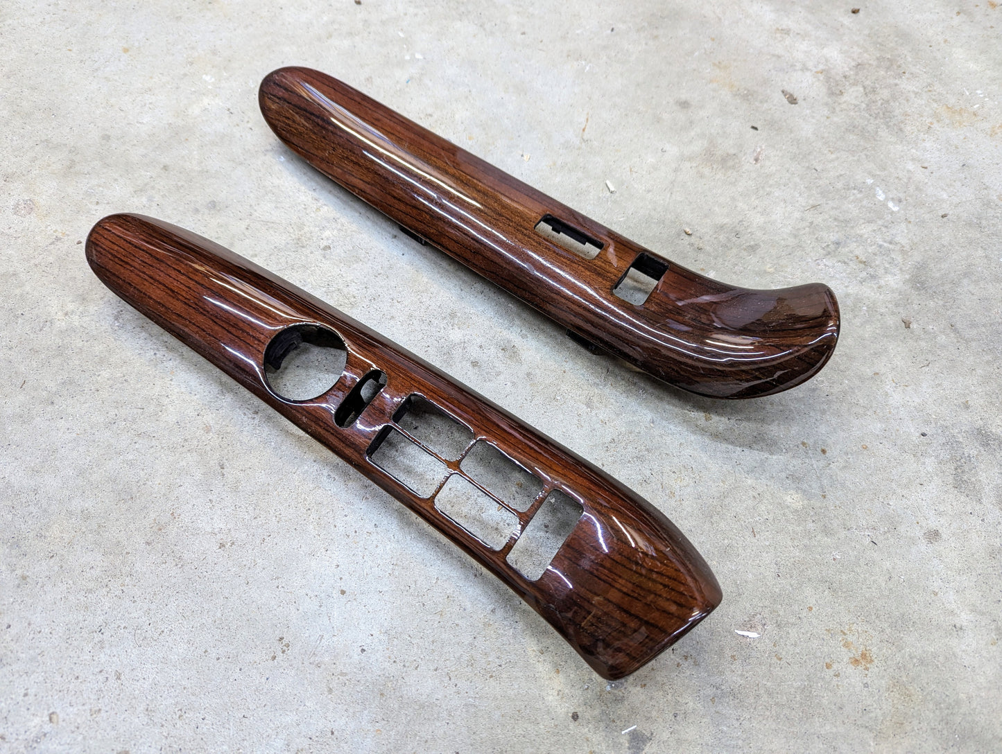 General Motors OEM Woodgrain Pair LH RH Power Switch Bezel for 1999-2000 Escalade Denali features glossy dark panels with cutouts for buttons, shown side by side on a concrete surface.