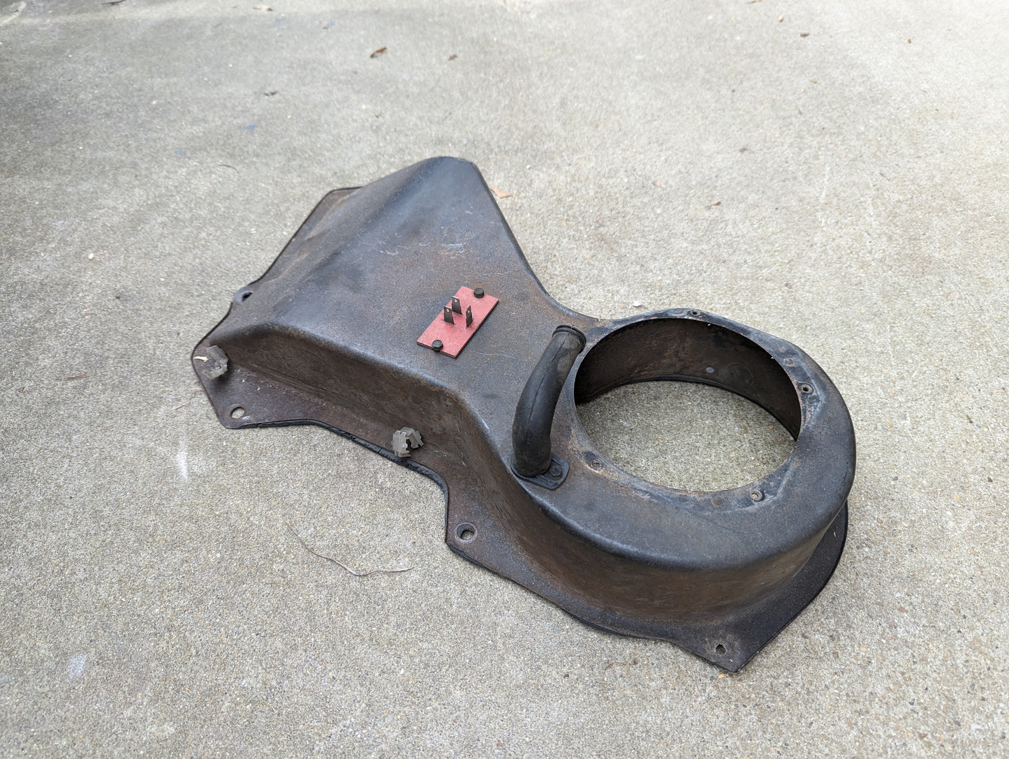 A General Motors OEM A/C Delete Heater Box & Control Panel for 1982-1985 S10 and Blazer is shown on a concrete surface. The used part appears worn, with visible rust and a small red metal plate.