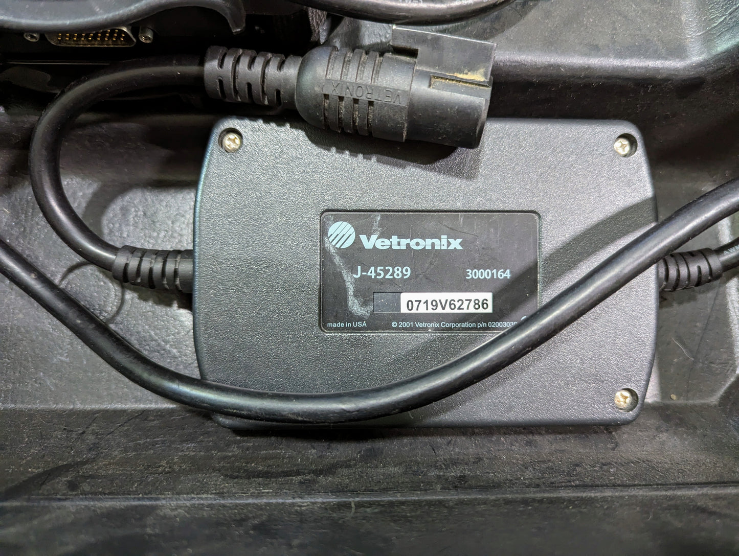 A black Vetronix TESTED Tech 2 Automotive Diagnostic Tool & Accessories for 1991-2013 GM Vehicles, with cables and identification codes including J-45289 and 0719V62786, is stored in a black compartment.
