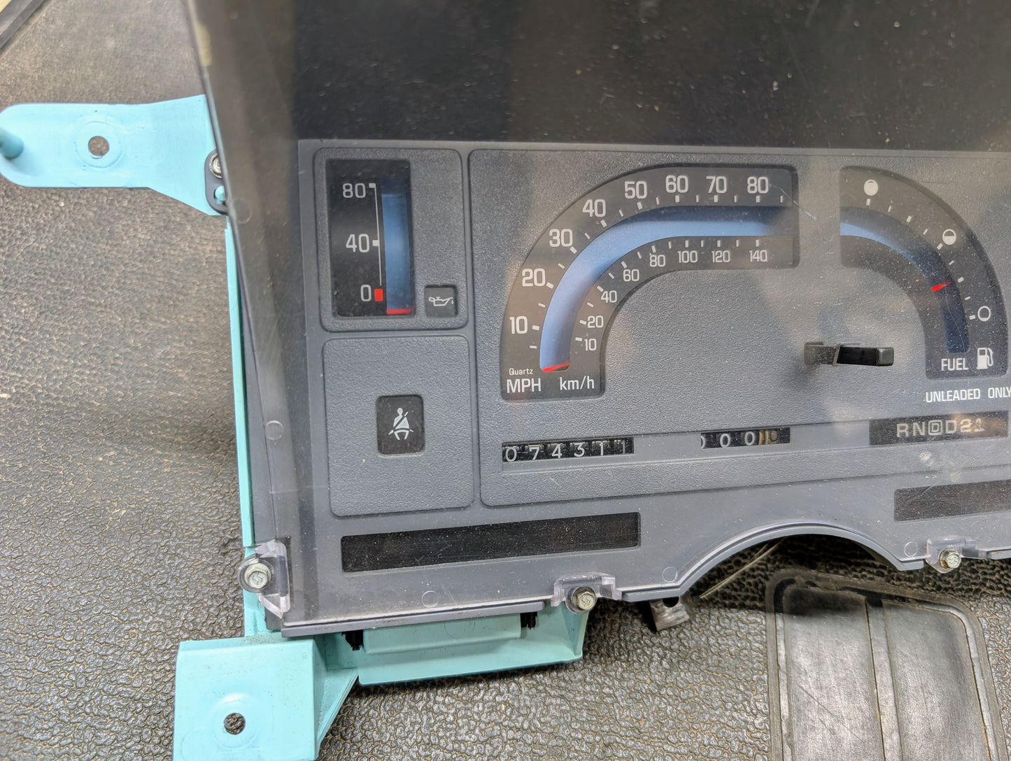A General Motors Low Mile 74K OEM Instrument Cluster with PRNDL for 1986-1994 Chevy S10 Blazer shows analog speedometer, fuel, and temp gauges. The odometer reads 73,311 miles, with the seat belt warning light illuminated.