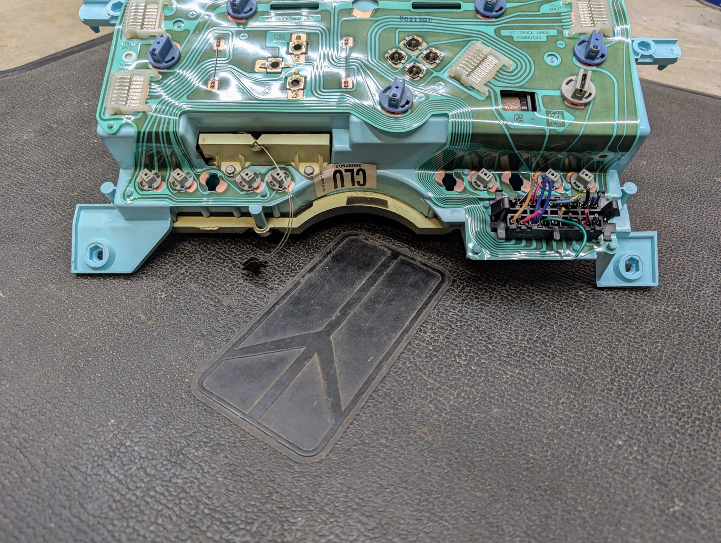 A close-up of a Low Mile 74K OEM Instrument Cluster with PRNDL for 1986-1994 Chevy S10 Blazer by General Motors, showing exposed circuitry and components on a black surface.