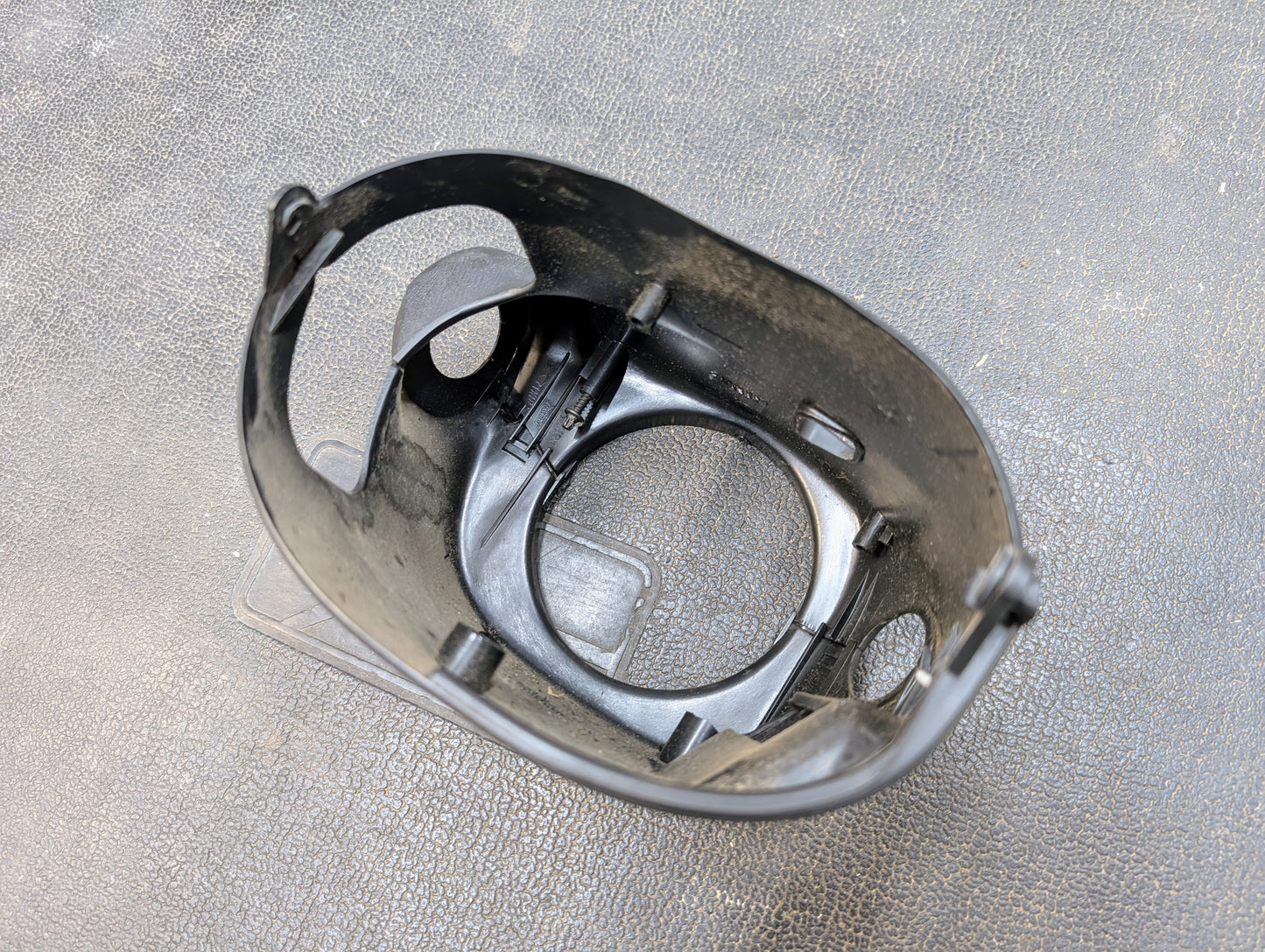 A close-up of a General Motors OEM Steering Column w/Tilt, Cruise Control, and Column Shift for 1998-2005 Chevy S10 Blazer, featuring multiple openings and attachment points, shown on a textured dark surface.
