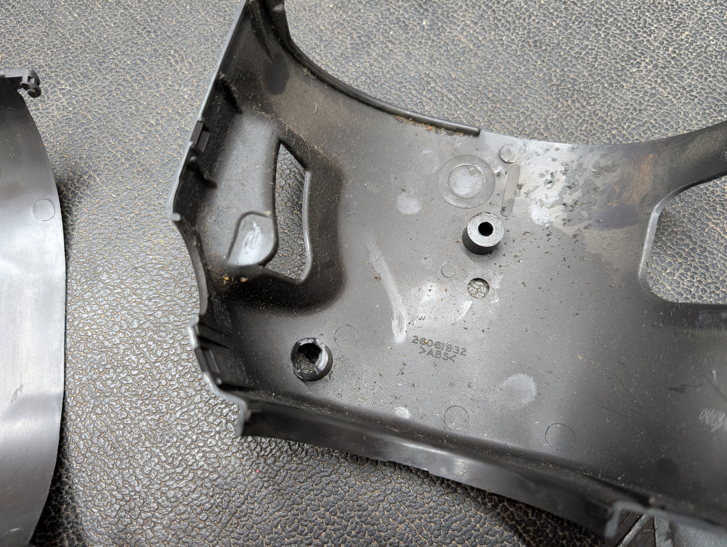 Close-up of a General Motors OEM Steering Column w/Tilt, Cruise Control, and Column Shift for 1998-2005 Chevy S10 Blazer, showing the black casing with mounting holes. Another similar part is partially visible on the left.