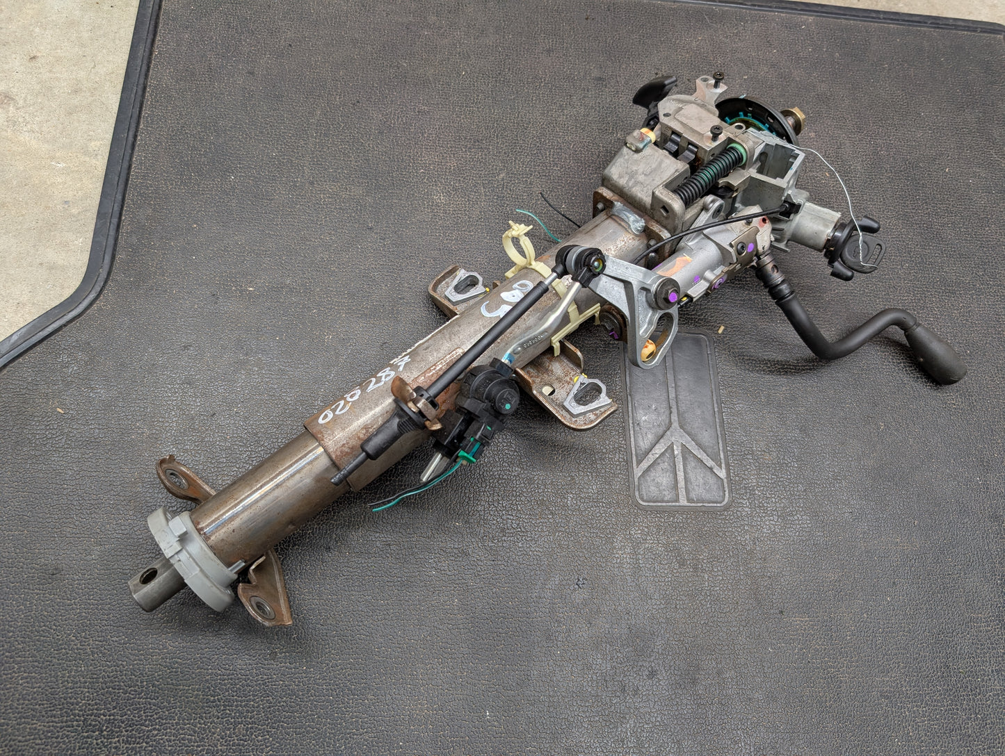 General Motors OEM Steering Column with tilt, cruise control, and column shift for 1998-2005 Chevy S10 Blazer and more; includes wiring, connectors, and components—shown on a textured black mat.