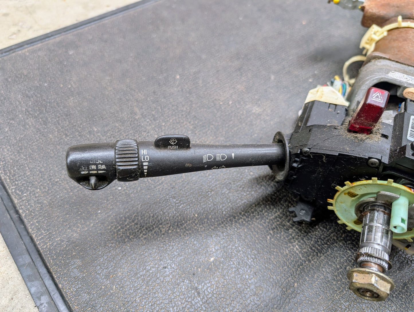 Close-up of a General Motors OEM Steering Column w/Tilt, Cruise Control, and Console Shift for 1998-2005 Chevy S10 Blazer, showing the turn signal and wiper lever with symbols and visible mechanical components.