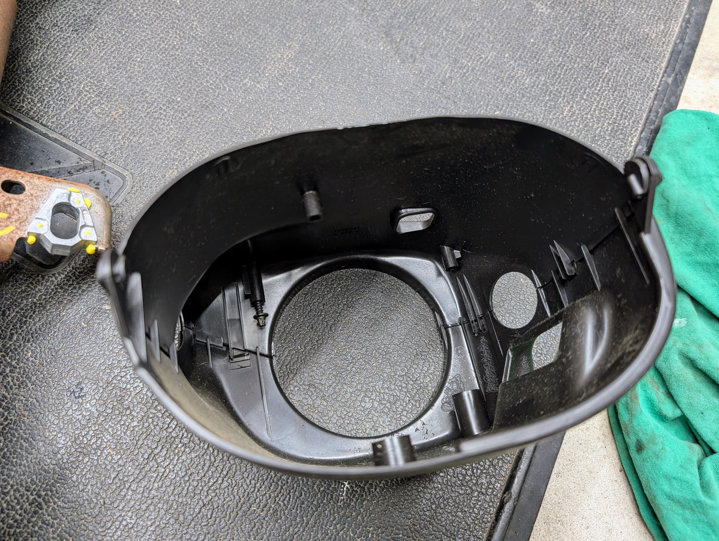A close-up of a black plastic cylindrical part from the General Motors OEM Steering Column w/Tilt, Cruise Control, and Console Shift for 1998-2005 Chevy S10 Blazer and more, shown resting on a textured black surface with a green cloth and rusted metal nearby.