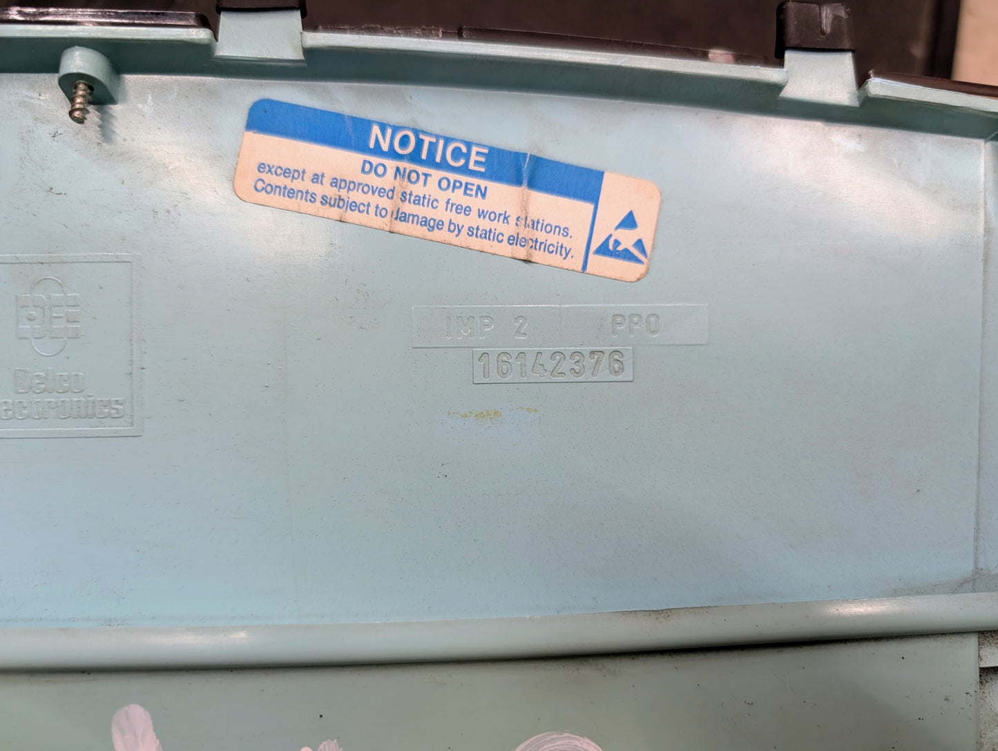 A close-up of the light blue casing of a General Motors OEM Instrument Cluster for 1986-1994 Chevy S10 Blazer shows a blue NOTICE label for static electricity, with IMP 2 PRO embossing and serial number 16142976 visible.
