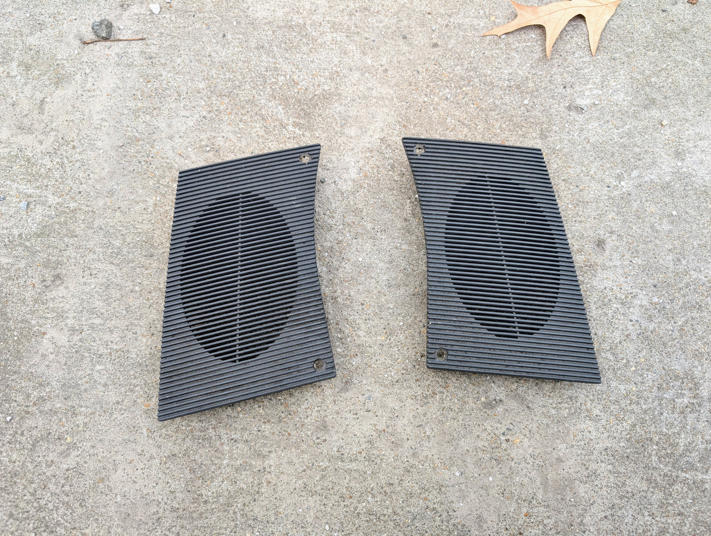 Two black speaker Grilles on a concrete surface