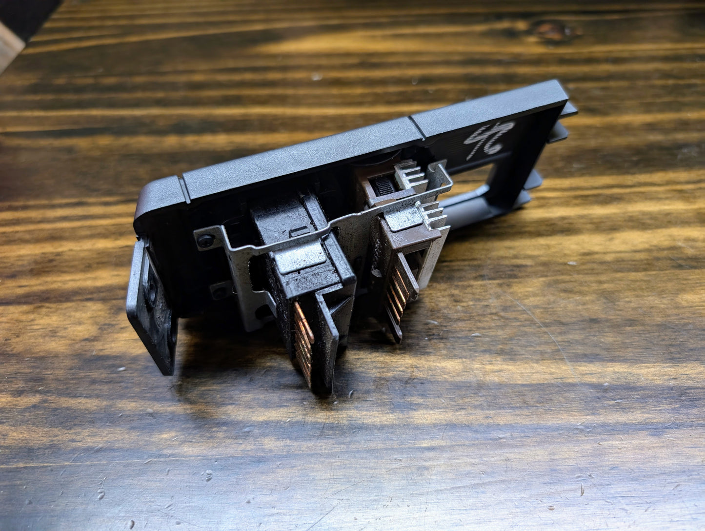 A close-up of a server network card with two damaged Ethernet ports, showing bent and blackened contacts, rests on wood—similar to a General Motors OEM Headlight Headlamp Switch for 1986-1994 Chevy S10, Blazer, GMC S15, Jimmy awaiting replacement.