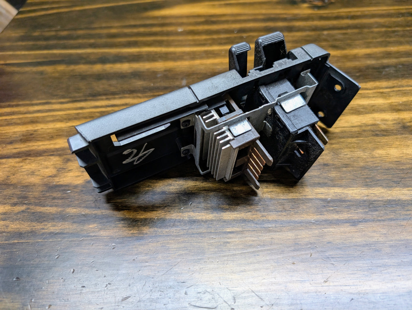 A close-up of a General Motors OEM Headlight Headlamp Switch for 1986-1994 Chevy S10, Blazer, GMC S15, Jimmy, with connectors and mounting holes, shown on a wooden surface.
