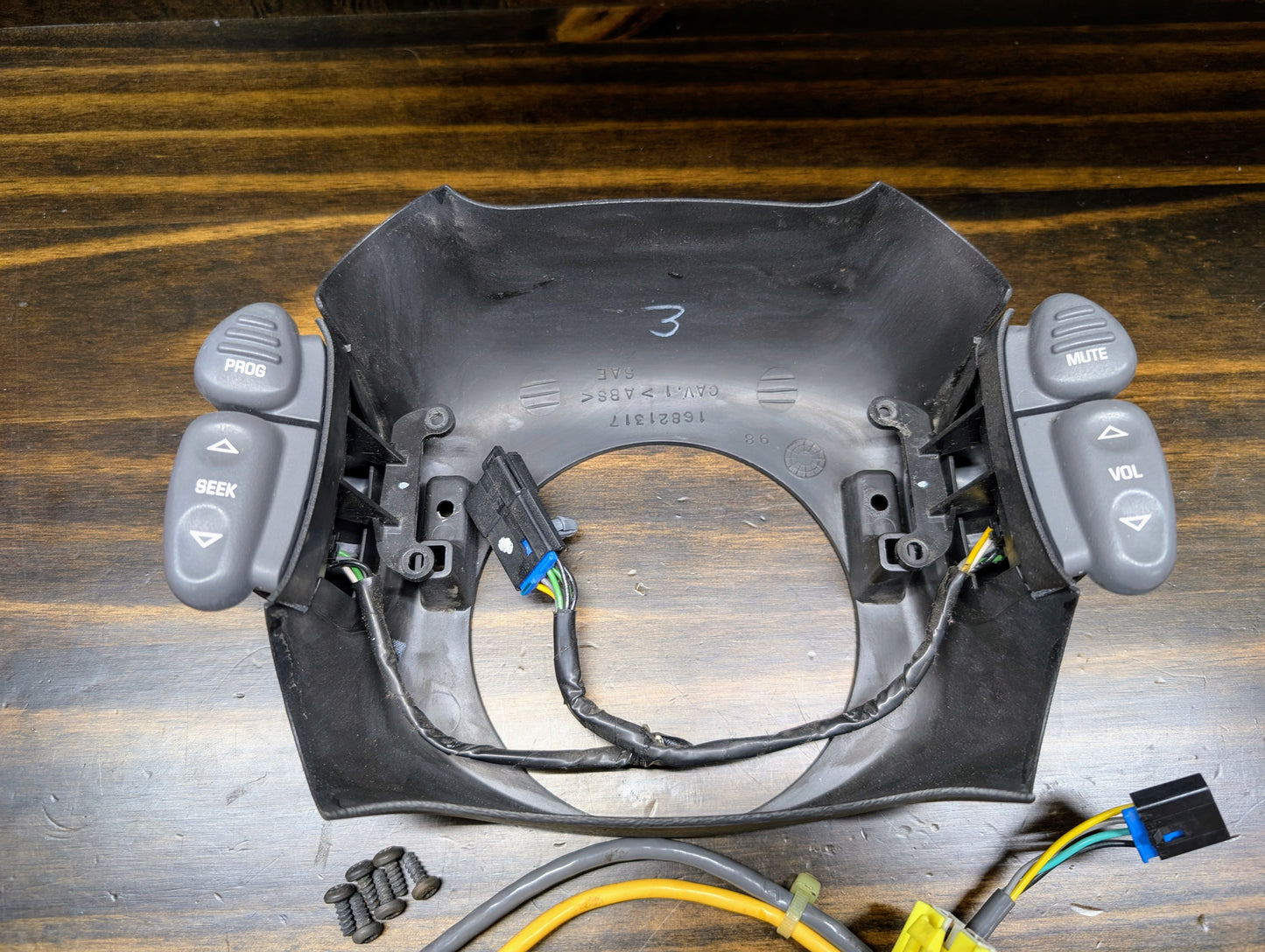 A General Motors KIT Steering Wheel Radio Controls & Clock Spring for 1999 Chevy S10, Blazer, and more rests on a wooden surface with wiring, connectors, and several screws nearby.