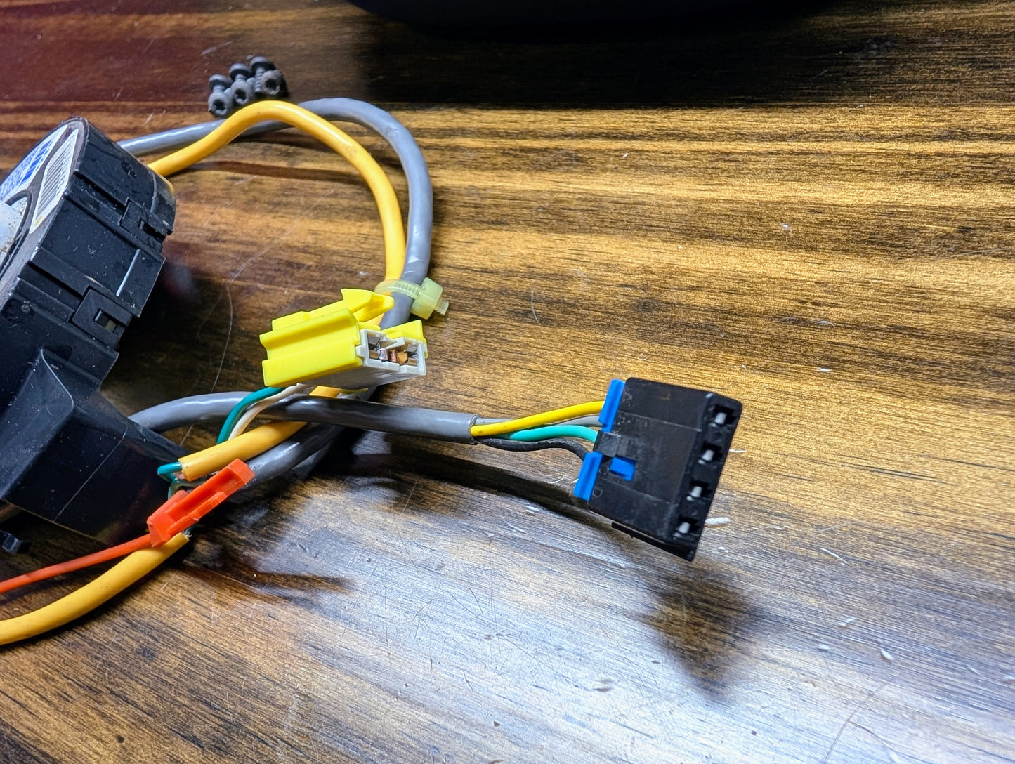 Close-up of electrical wires and connectors from the General Motors KIT Steering Wheel Radio Controls & Clock Spring for 1999 Chevy S10, Blazer, and more. Features color-coded wires, a yellow/clear plastic connector, and a black multi-pin connector.