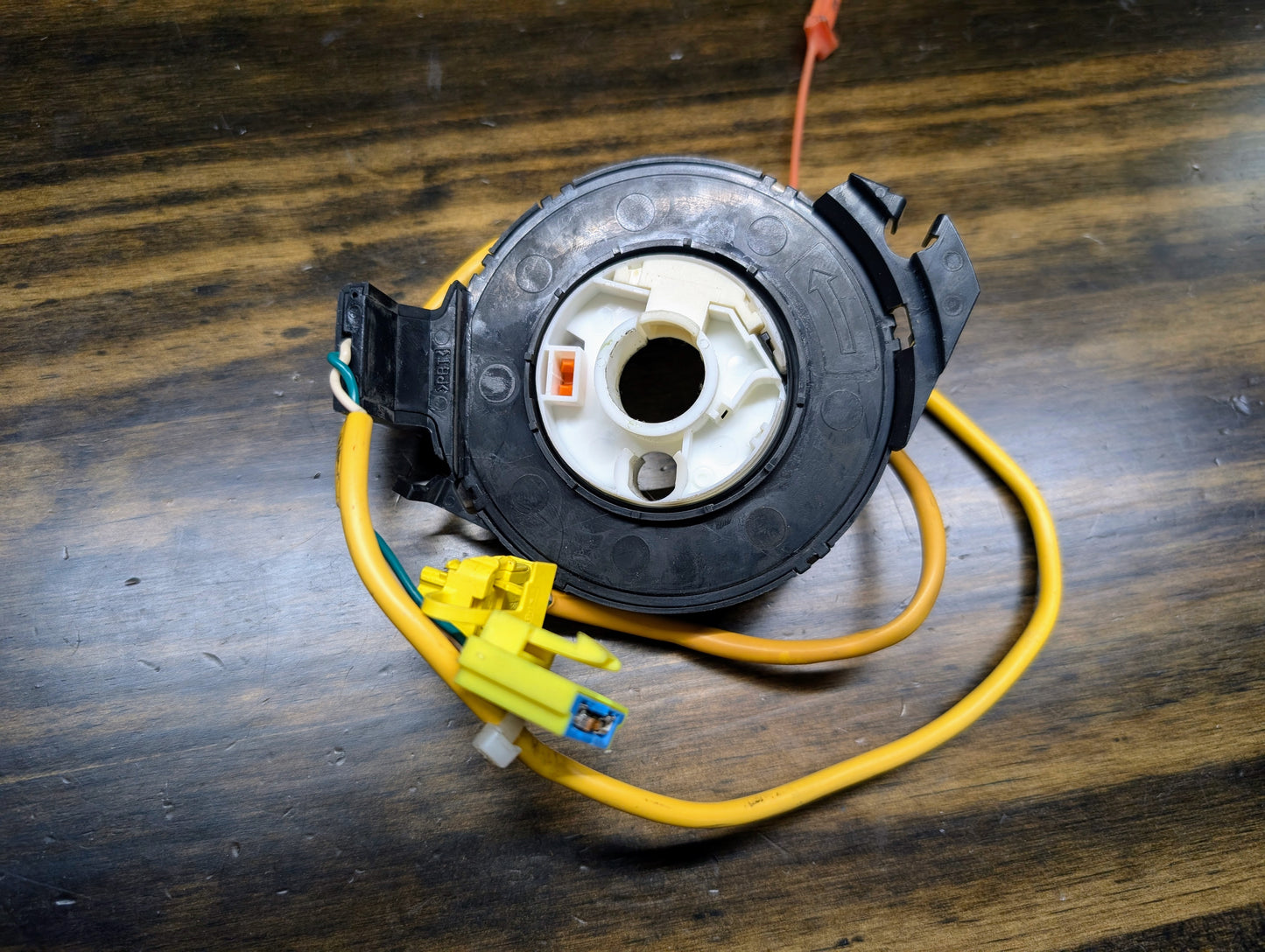 A General Motors OEM SRS clock spring for 2000-2003 Chevy S10 Blazer, with yellow/orange wires and plastic connectors, displays part numbers 26088306, 26087310, and 26083473 along with directional symbols on its black housing.