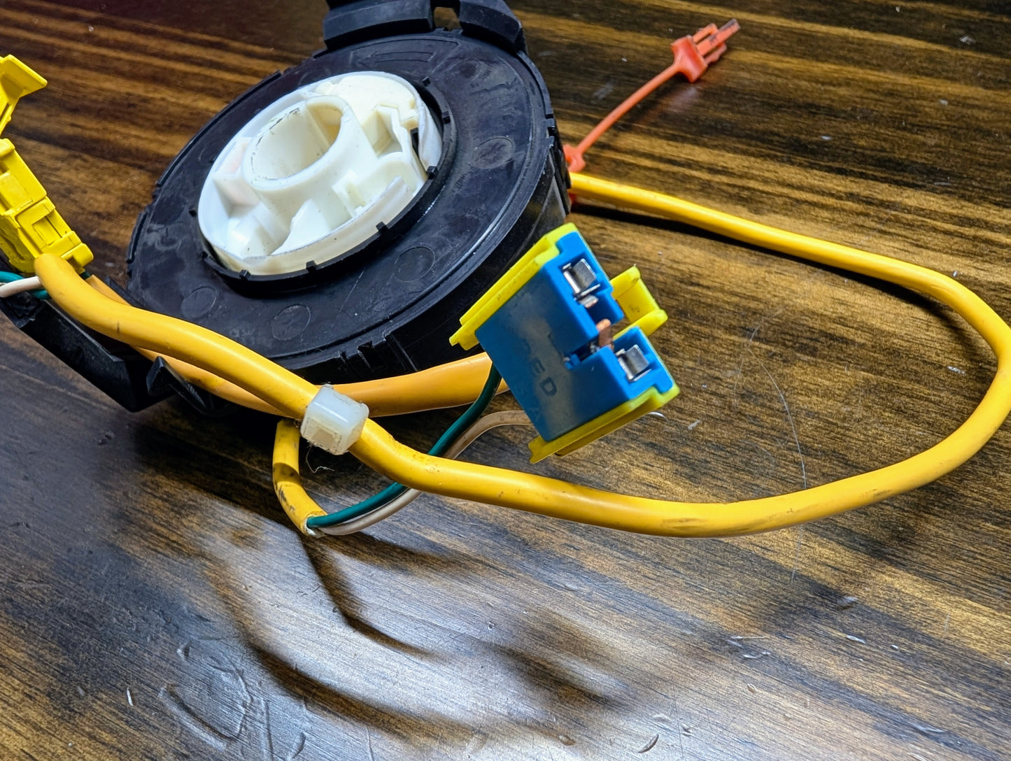 A close-up of a TESTED General Motors OEM SRS clock spring for 2000-2003 Chevy S10 Blazer, featuring yellow wiring, blue connectors, and a white center. Compatible with part numbers 26088306, 26087310, and 26083473.
