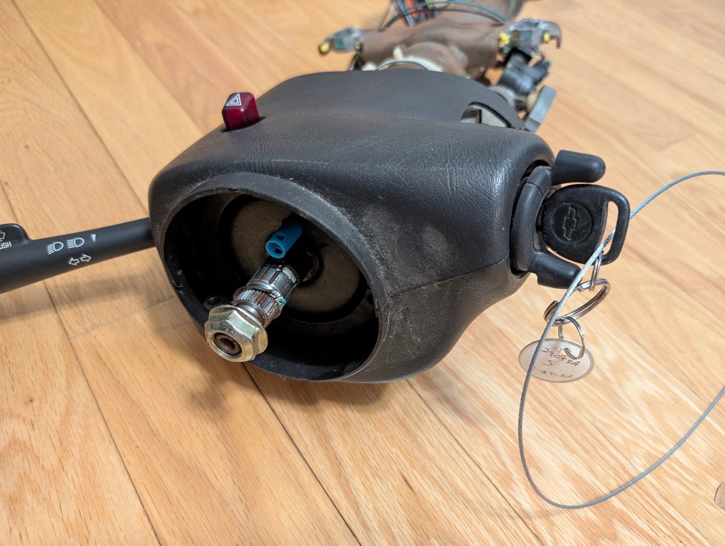 A close-up of a General Motors OEM Steering Column w/Tilt, Cruise Control, and Column Shift for 1998-2005 Chevy S10 Blazer, showing the ignition with keys, turn signal lever, cruise control switch, and exposed parts.
