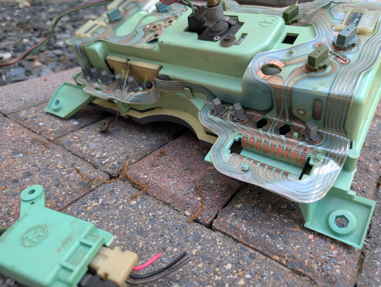 A close-up shows a General Motors OEM Instrument Cluster with Mechanical Speedo & PRNDL for 1986-1989 Chevy S10 Blazer on a paved surface, with wiring and connectors visible, plus an extra green connector in the lower left corner.