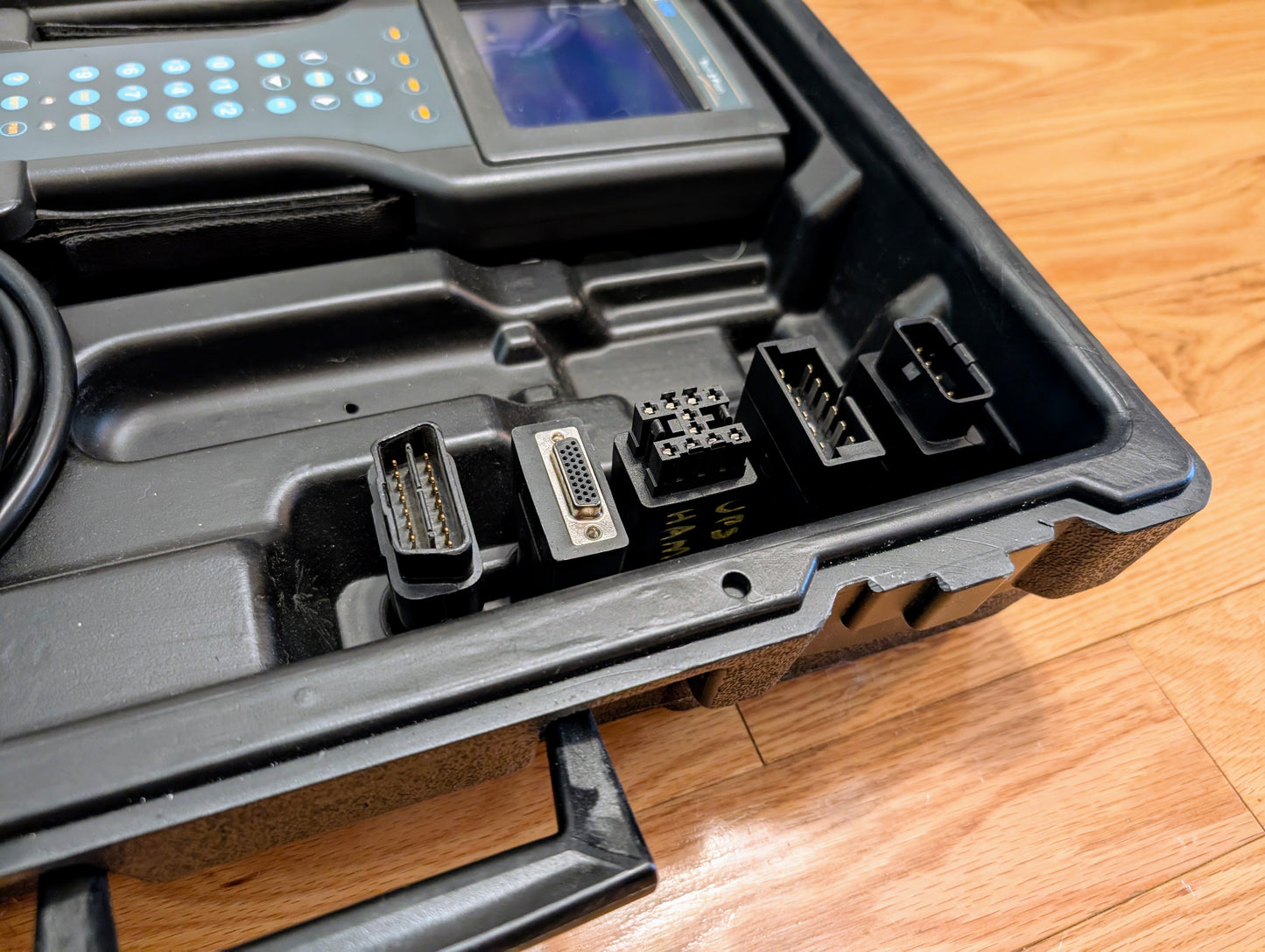 A black carrying case holds the Vetronix TESTED Tech 2 Automotive Diagnostic Tool & Accessories for 1991-2013 GM vehicles, featuring a screen, keypad, and connector ports—ideal for OBD2 code scanning and GM diagnostics.