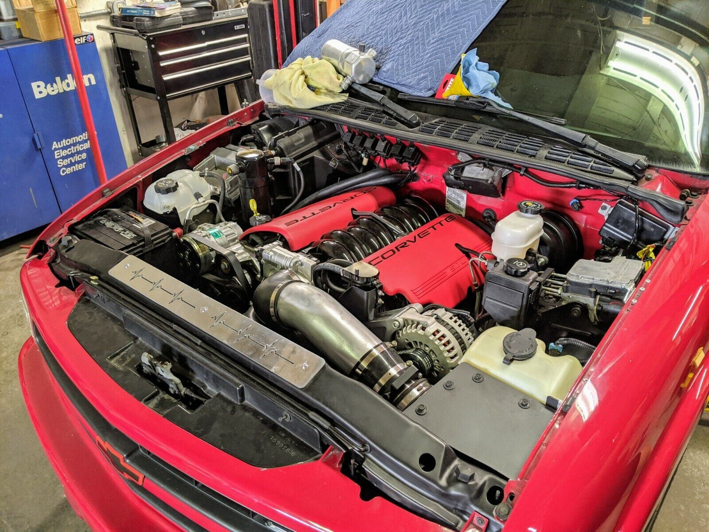 A red Chevrolet S10, hood open in a workshop, reveals a Corvette engine with a clean bay and The Ugly Truckling’s 1995-2005 Chevy S10 Blazer LS Swap Cold Air Box Custom Fabricated for a factory look; tools and towels are nearby.