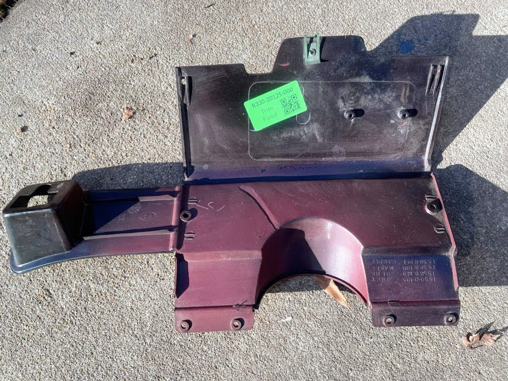 A red General Motors OEM lower dash trim knee bolster for 1986–1993 Chevy S10 Blazer/GMC S15 rests on concrete in sunlight, showing molded details and part numbers.